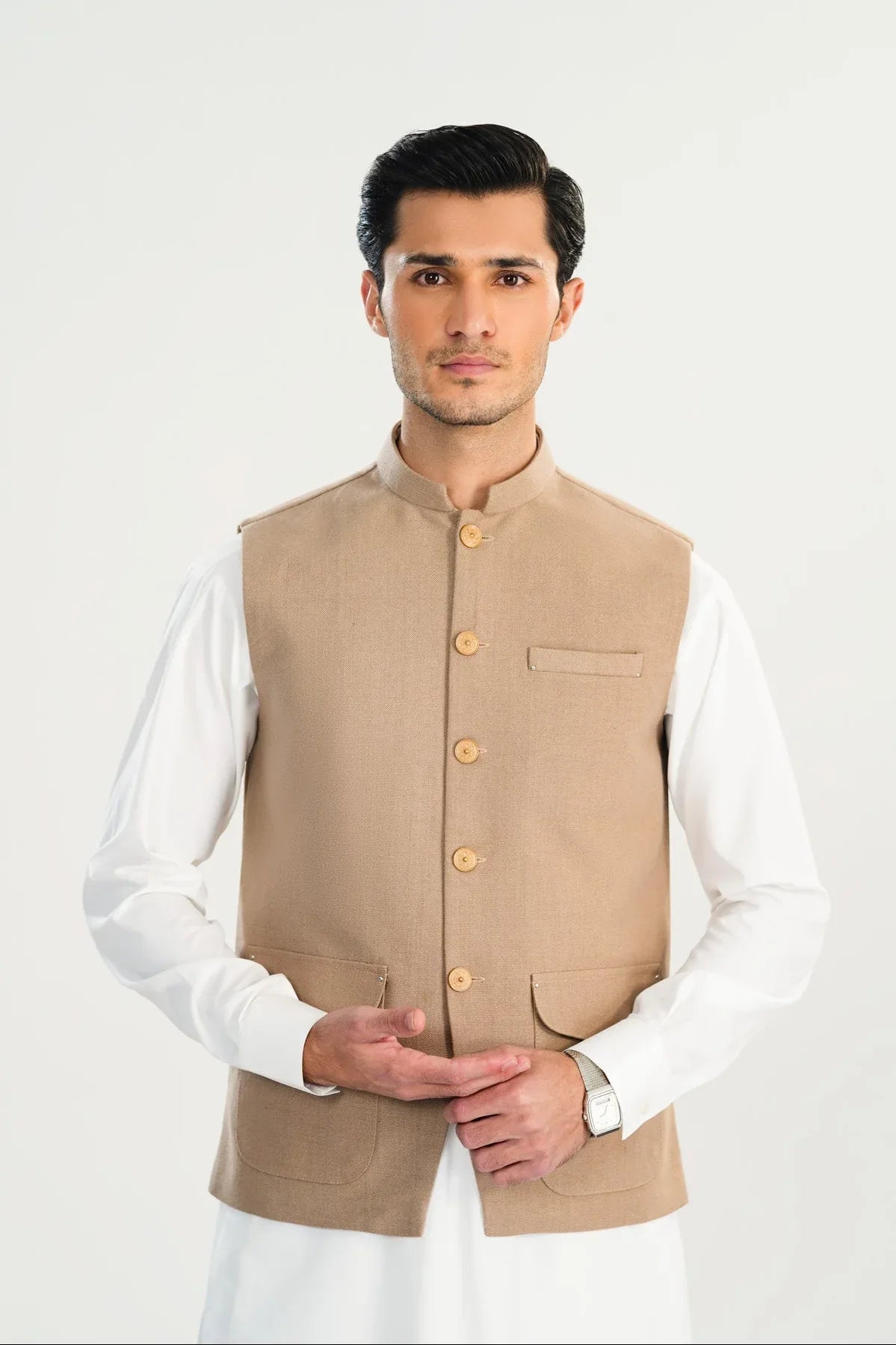 Man wearing a beige vest over a white shirt on a white background