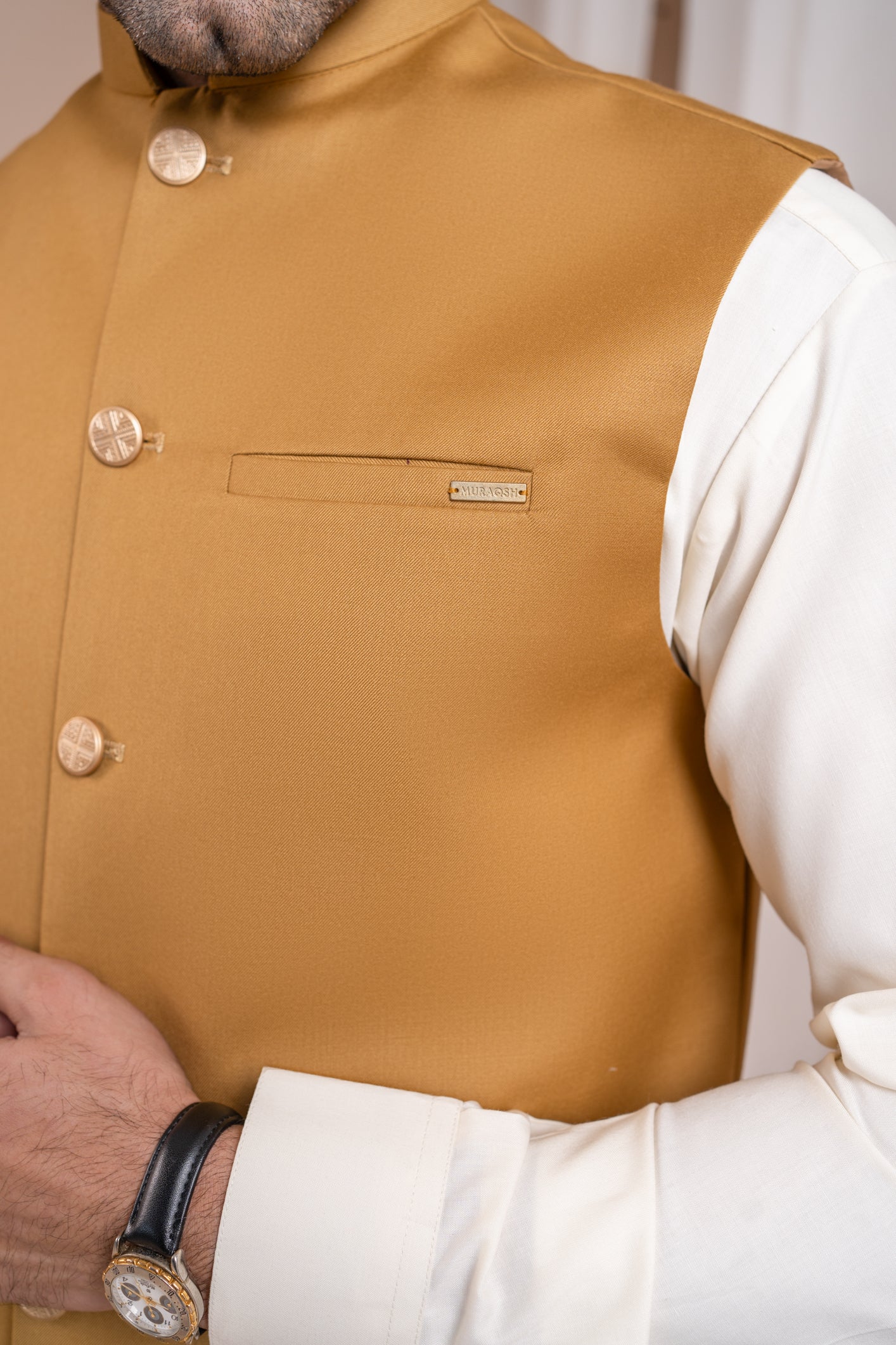A man wearing a camel suiting waistcoat with a straight cut and classic button design over a white shirt.