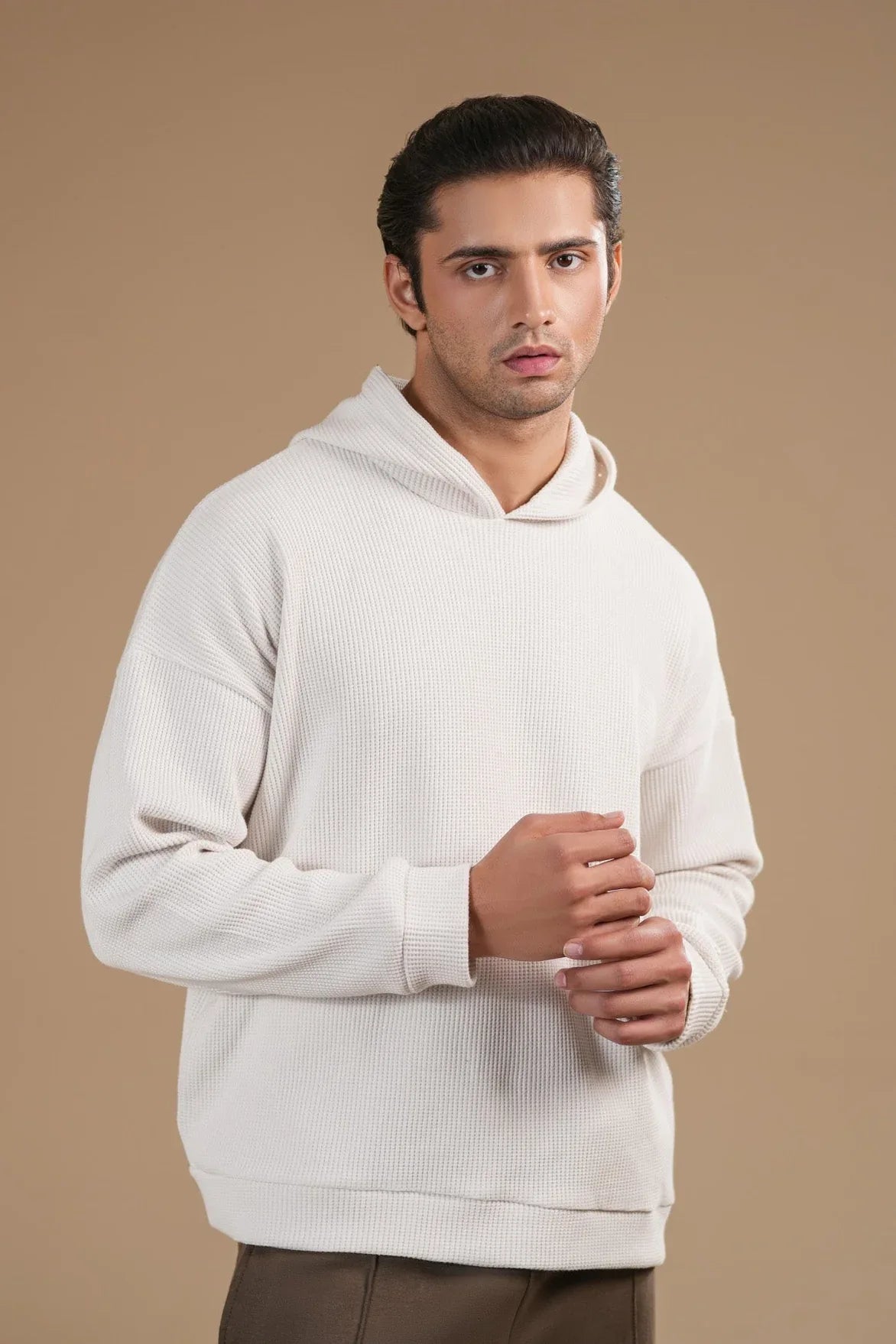 Man wearing a white hoodie against a beige background
