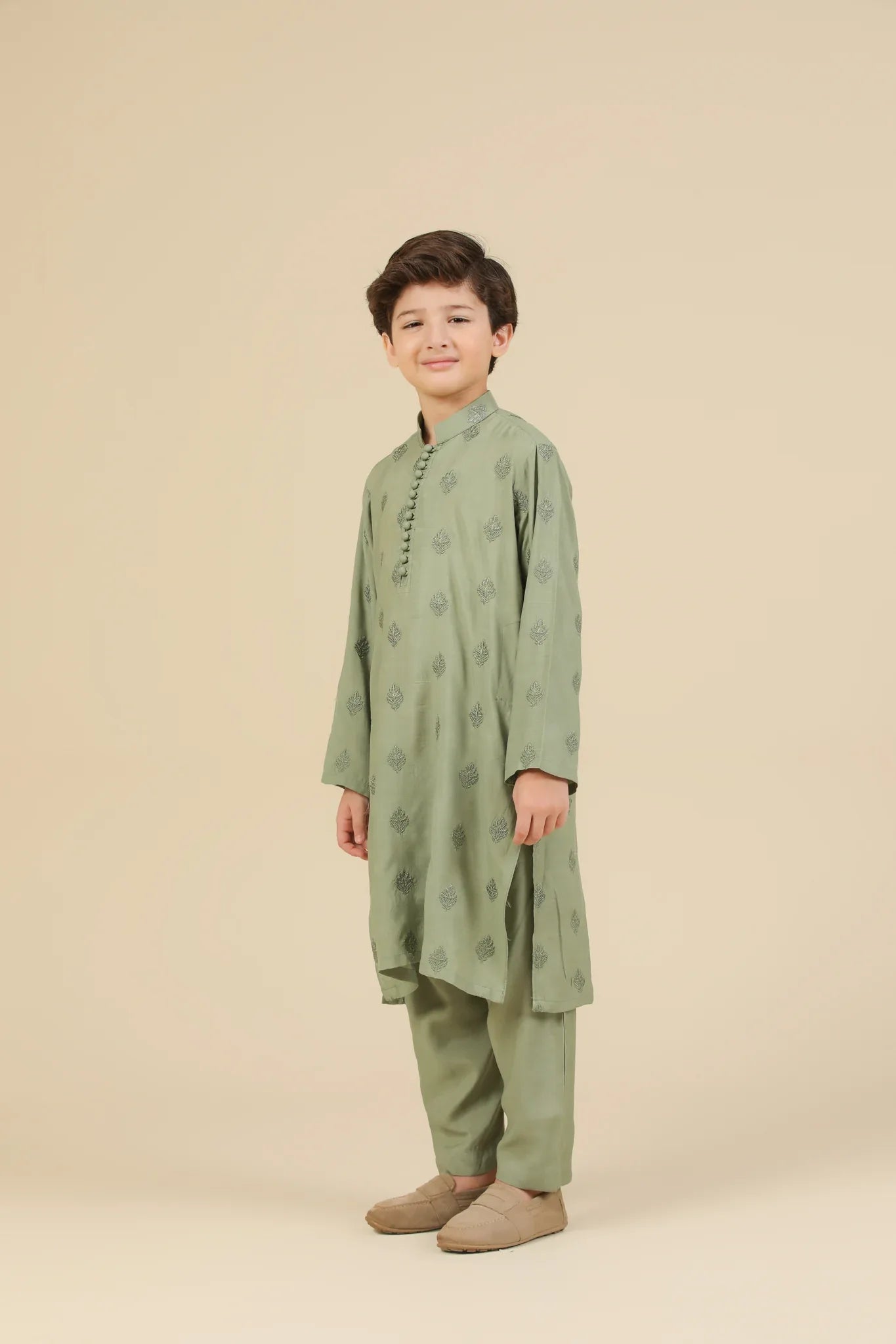 Child wearing a mint green raw silk embroidered kurta trouser with a beige background