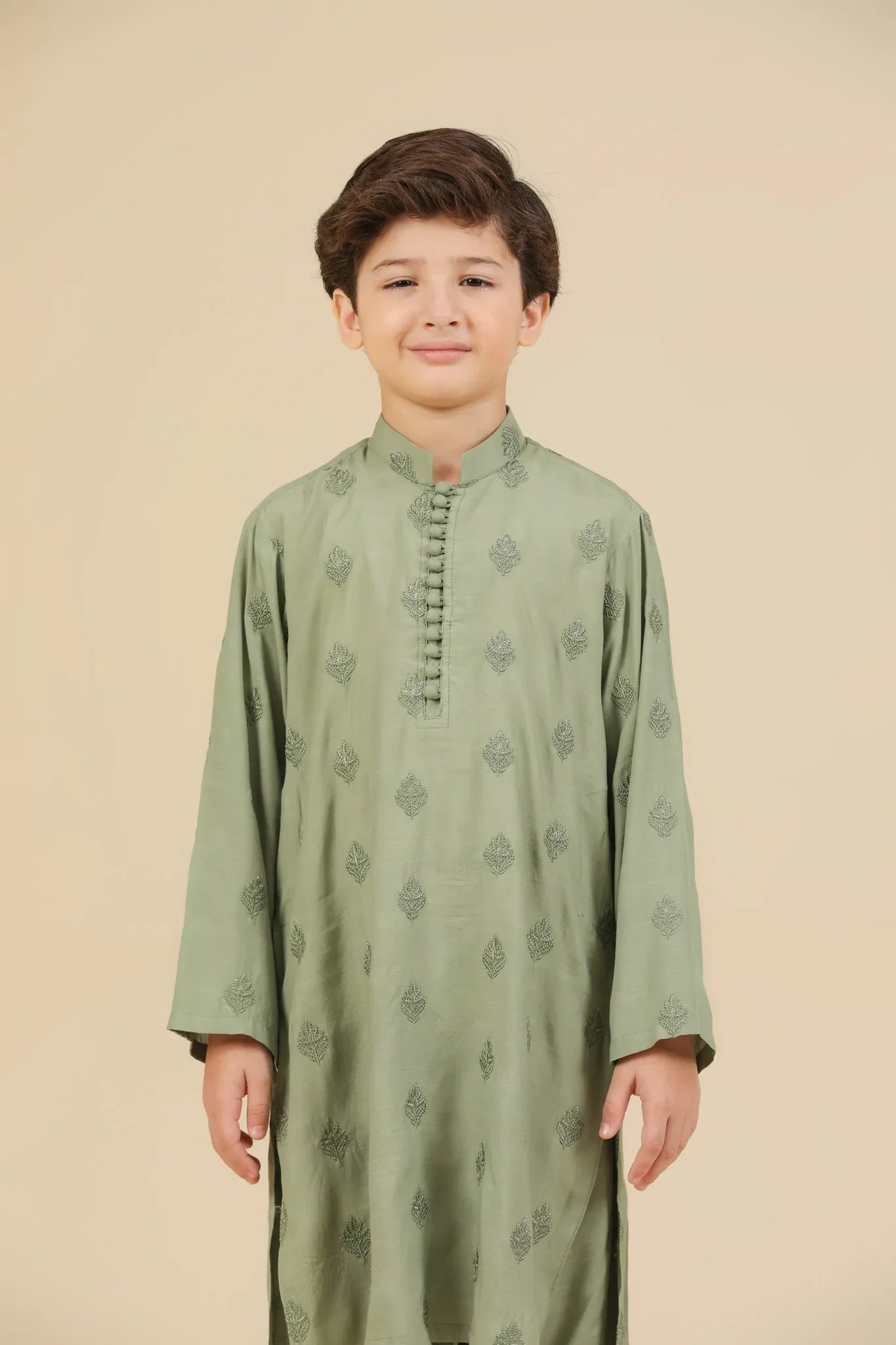 Child wearing a mint green raw silk embroidered kurta trouser with a beige background