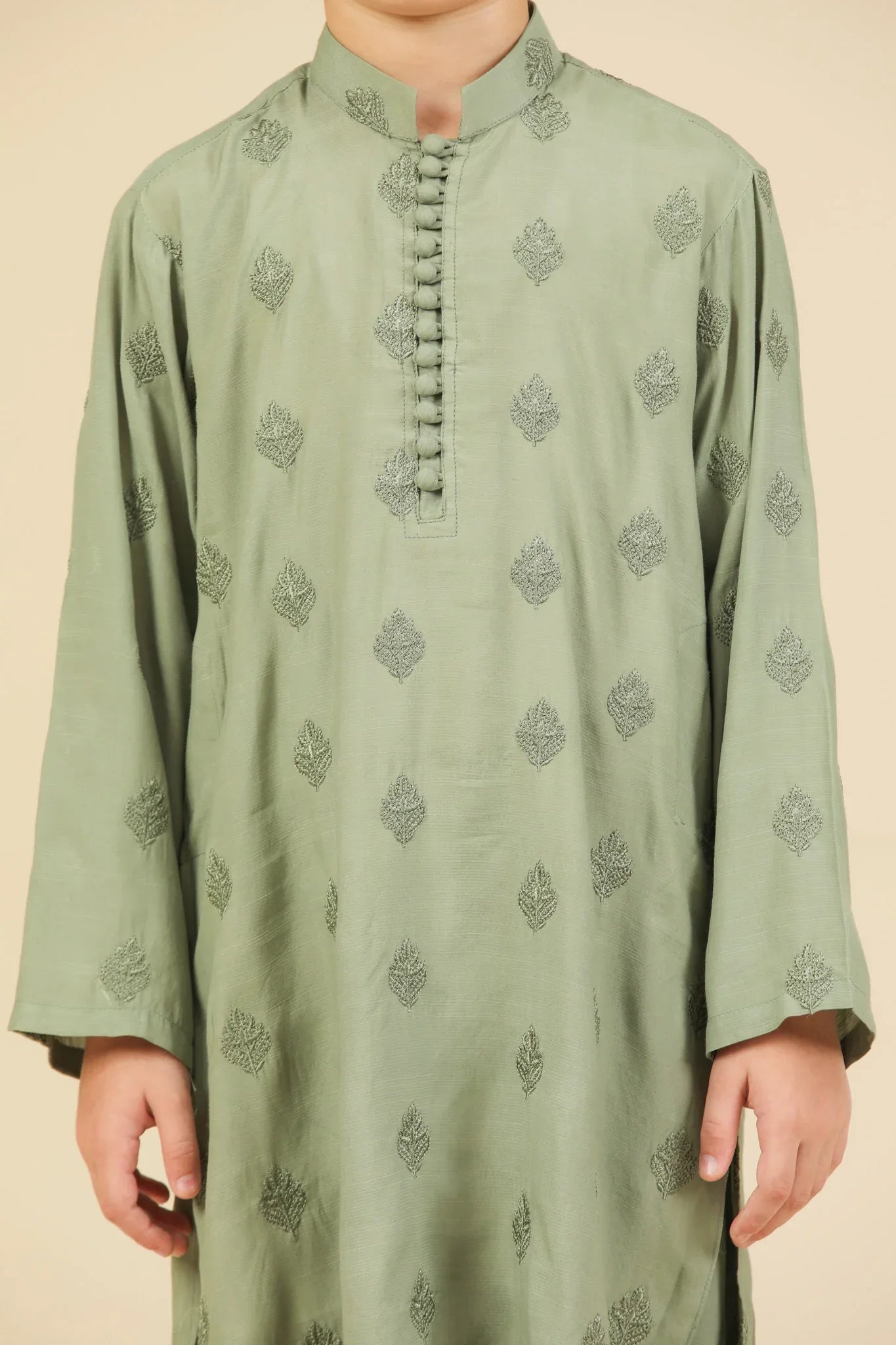 Child wearing a mint green raw silk embroidered kurta trouser with a beige background