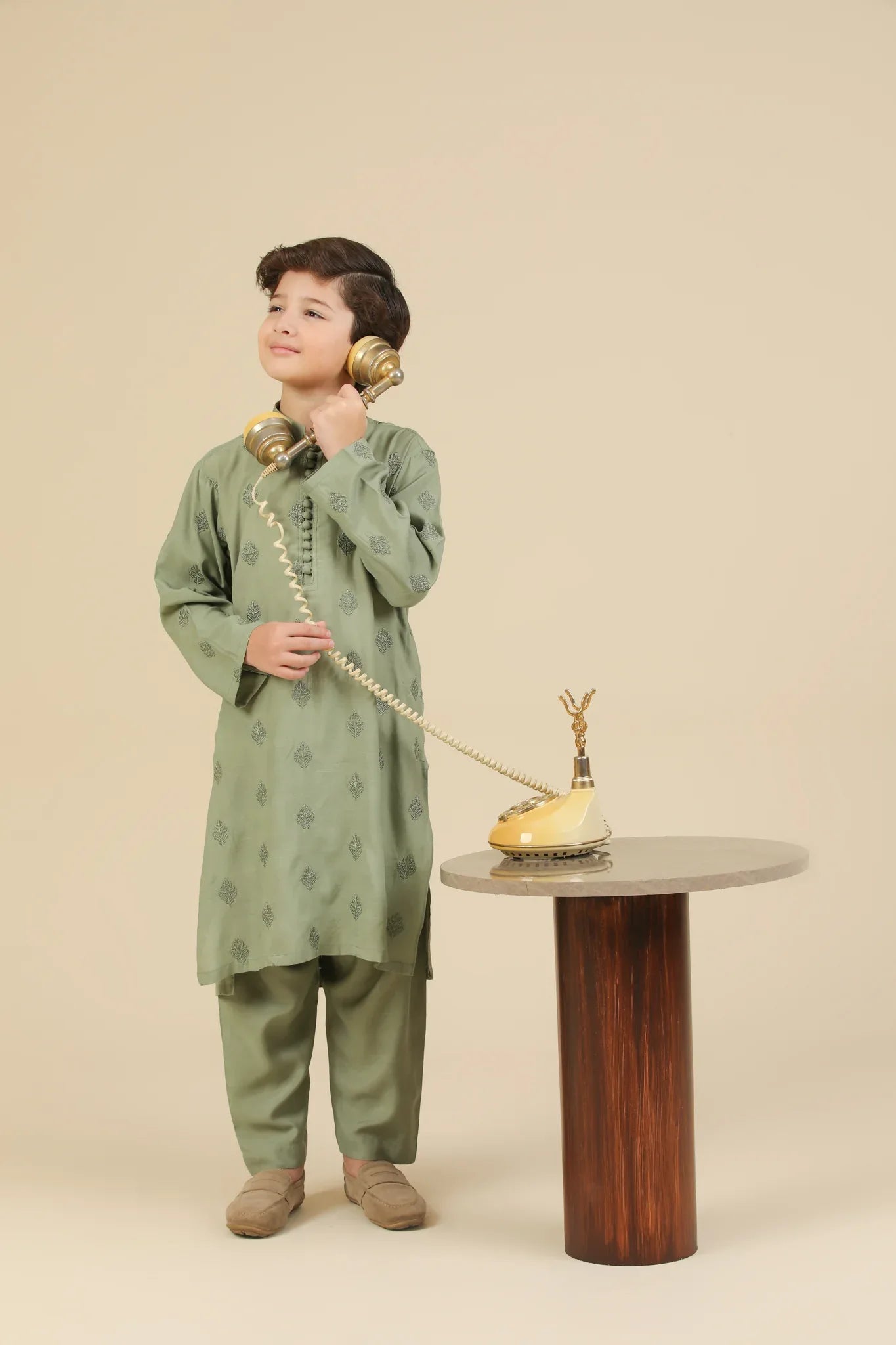 Child wearing a mint green raw silk embroidered kurta trouser with a beige background