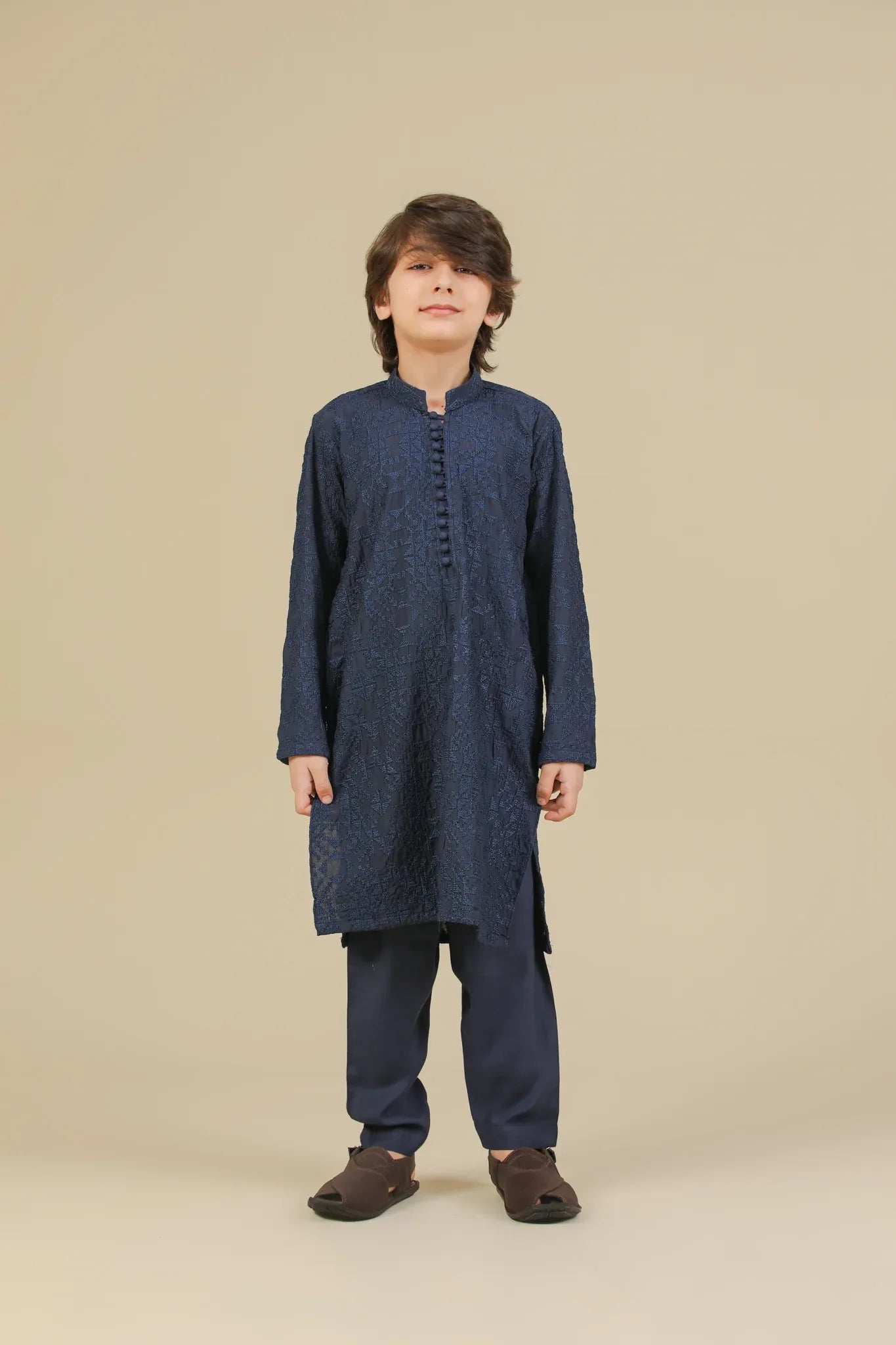 Child wearing a blue raw silk embroidered kurta trouser on a beige background