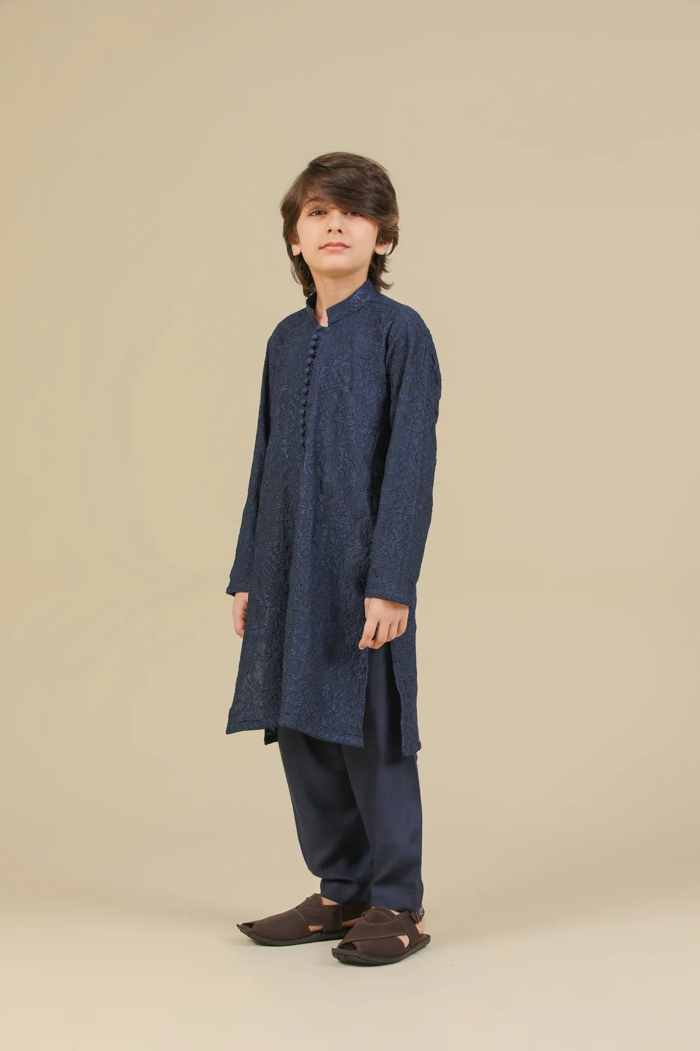 Child wearing a blue raw silk embroidered kurta trouser on a beige background
