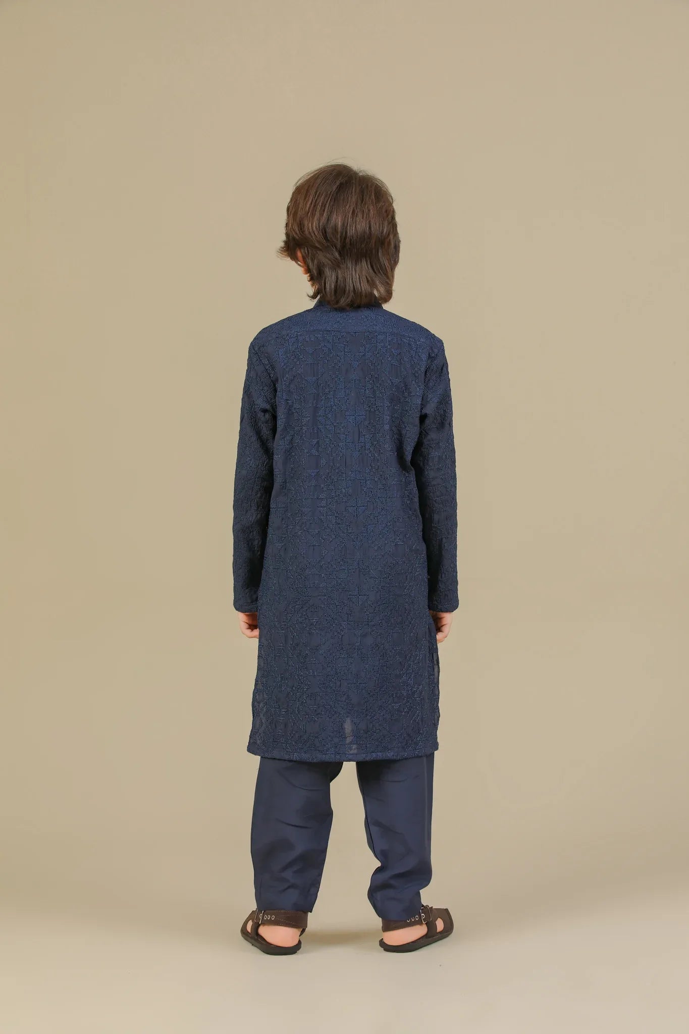 Child wearing a blue raw silk embroidered kurta trouser on a beige background