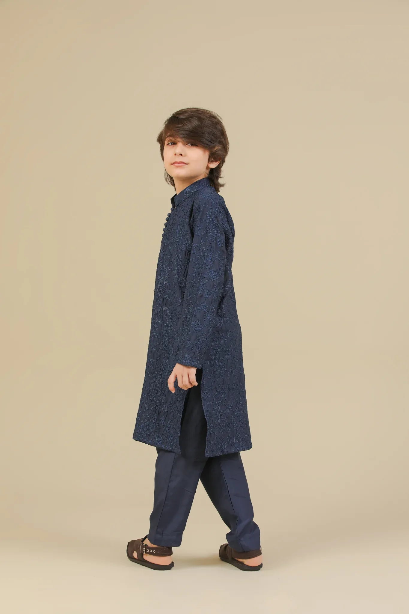 Child wearing a blue raw silk embroidered kurta trouser on a beige background