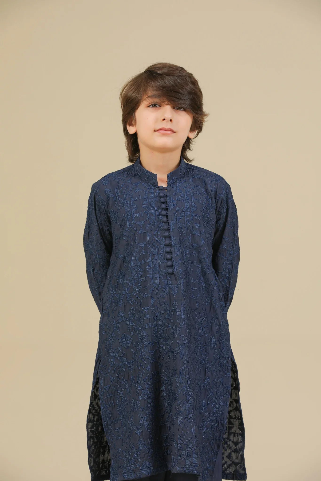 Child wearing a blue raw silk embroidered kurta trouser on a beige background