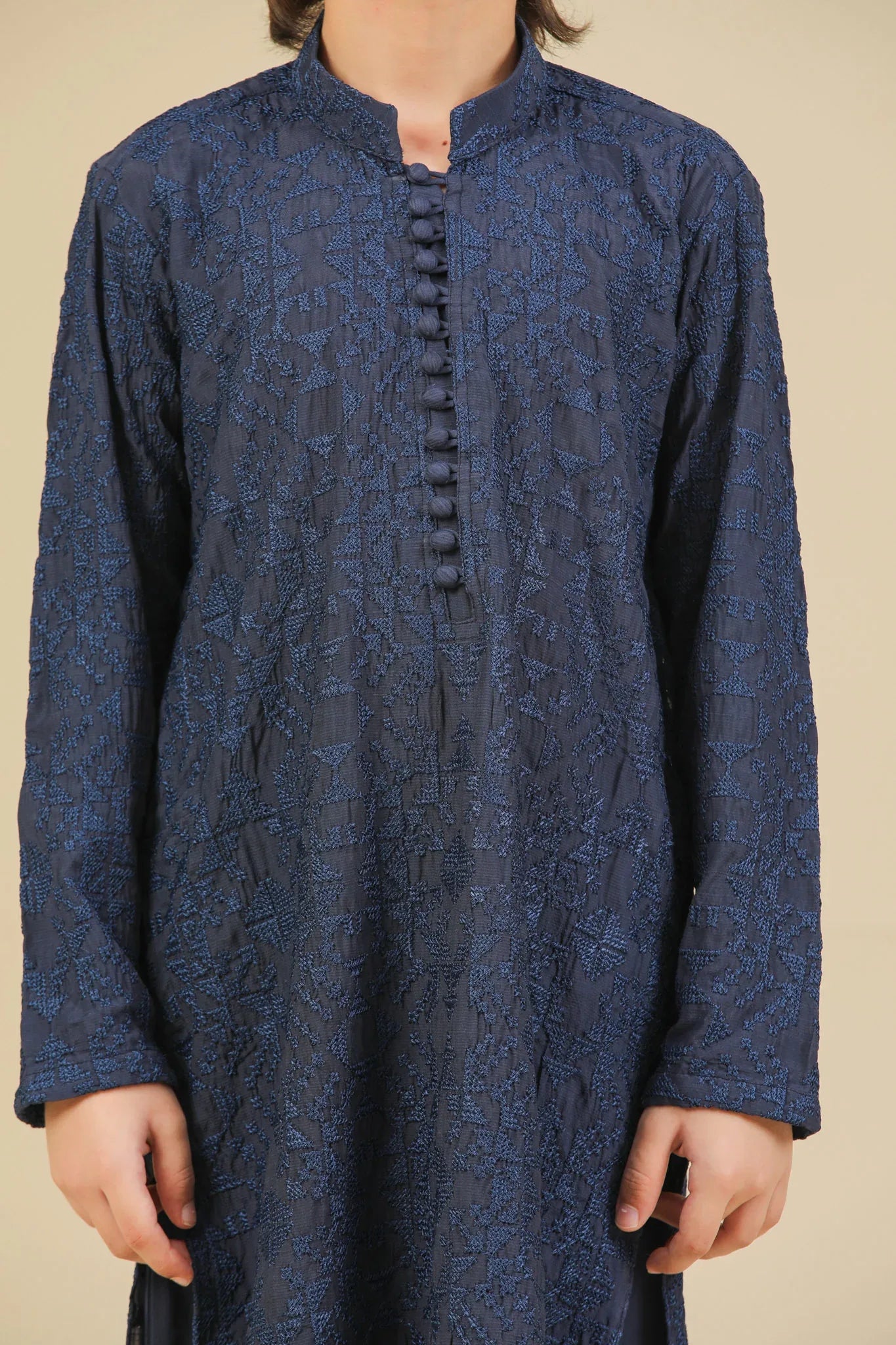 Child wearing a blue raw silk embroidered kurta trouser on a beige background