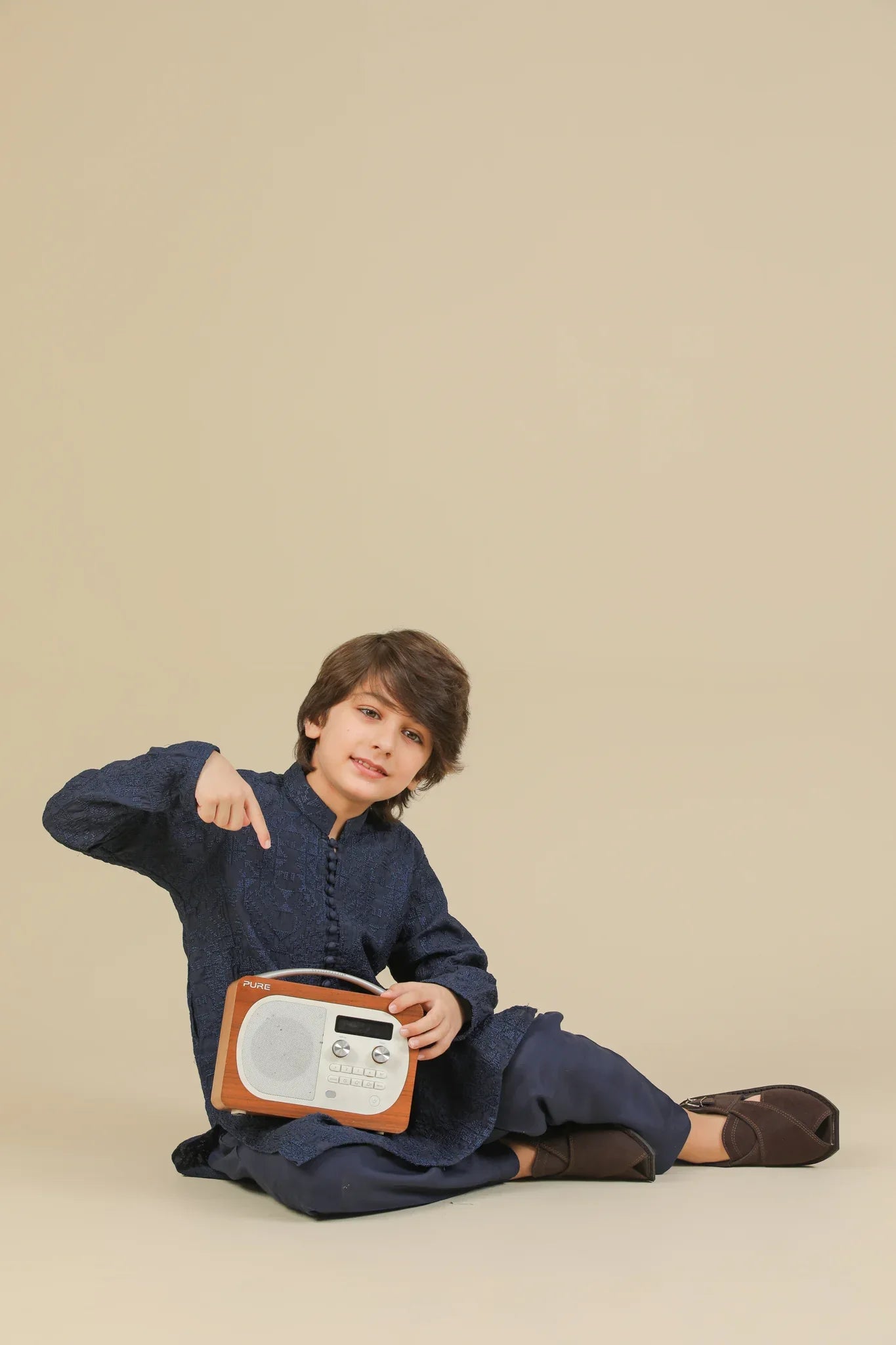 Child wearing a blue raw silk embroidered kurta trouser on a beige background