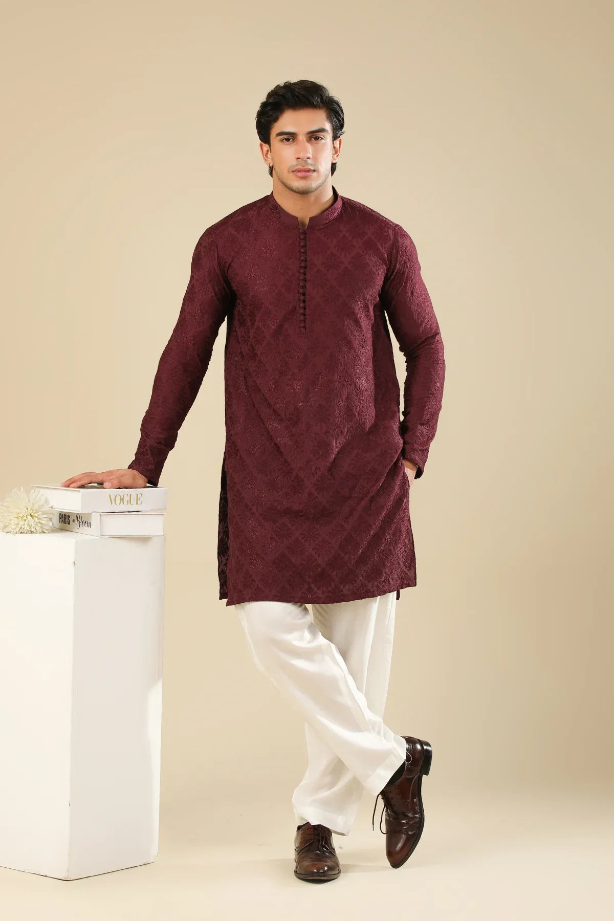 Man wearing a maroon embroidered kurta trouser with a beige background