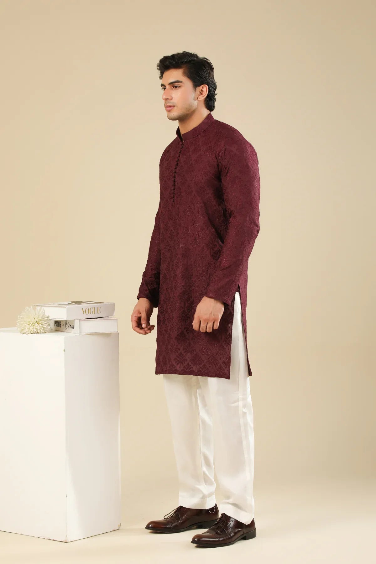 Man wearing a maroon embroidered kurta trouser with a beige background