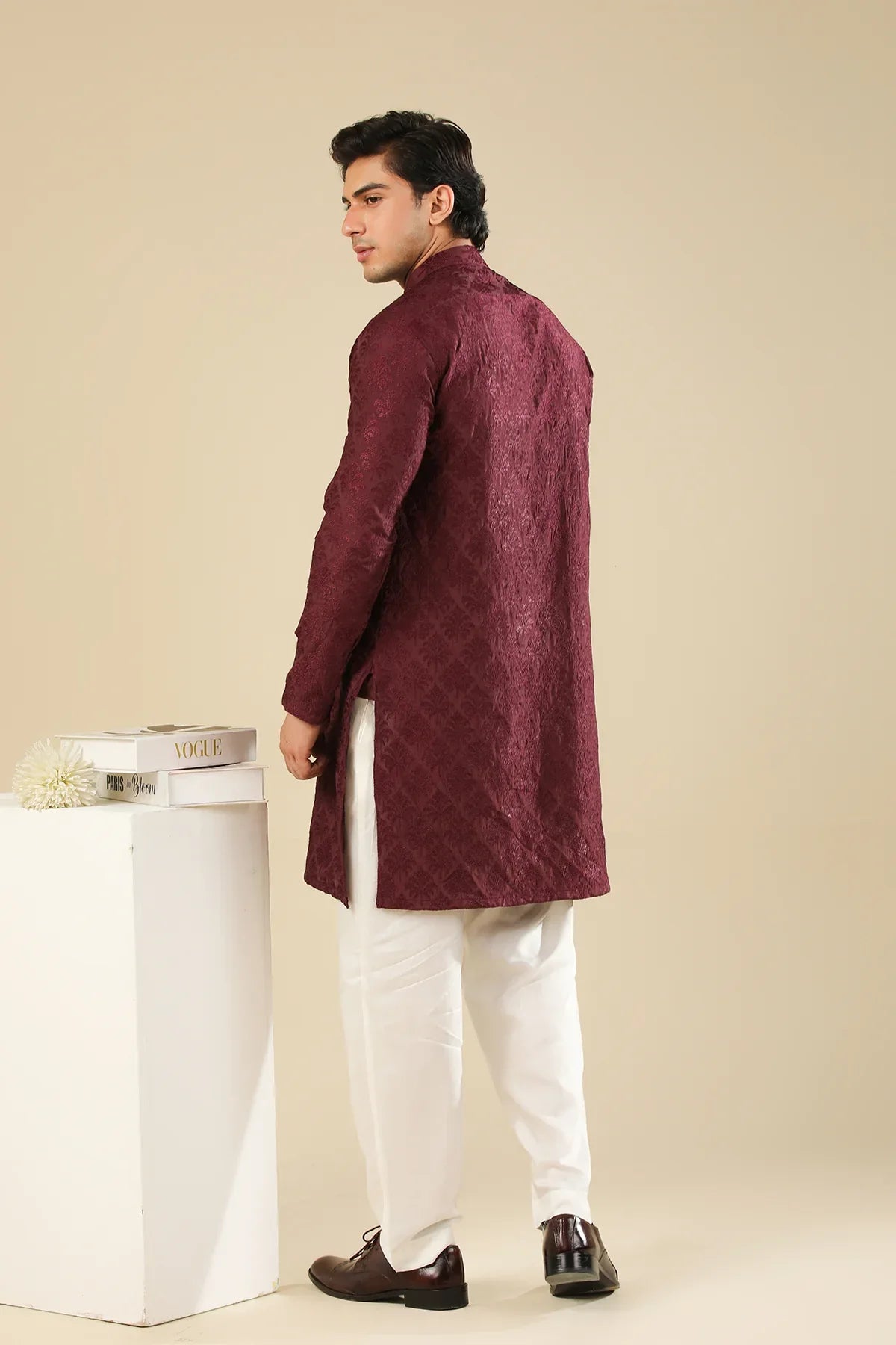 Man wearing a maroon embroidered kurta trouser with a beige background