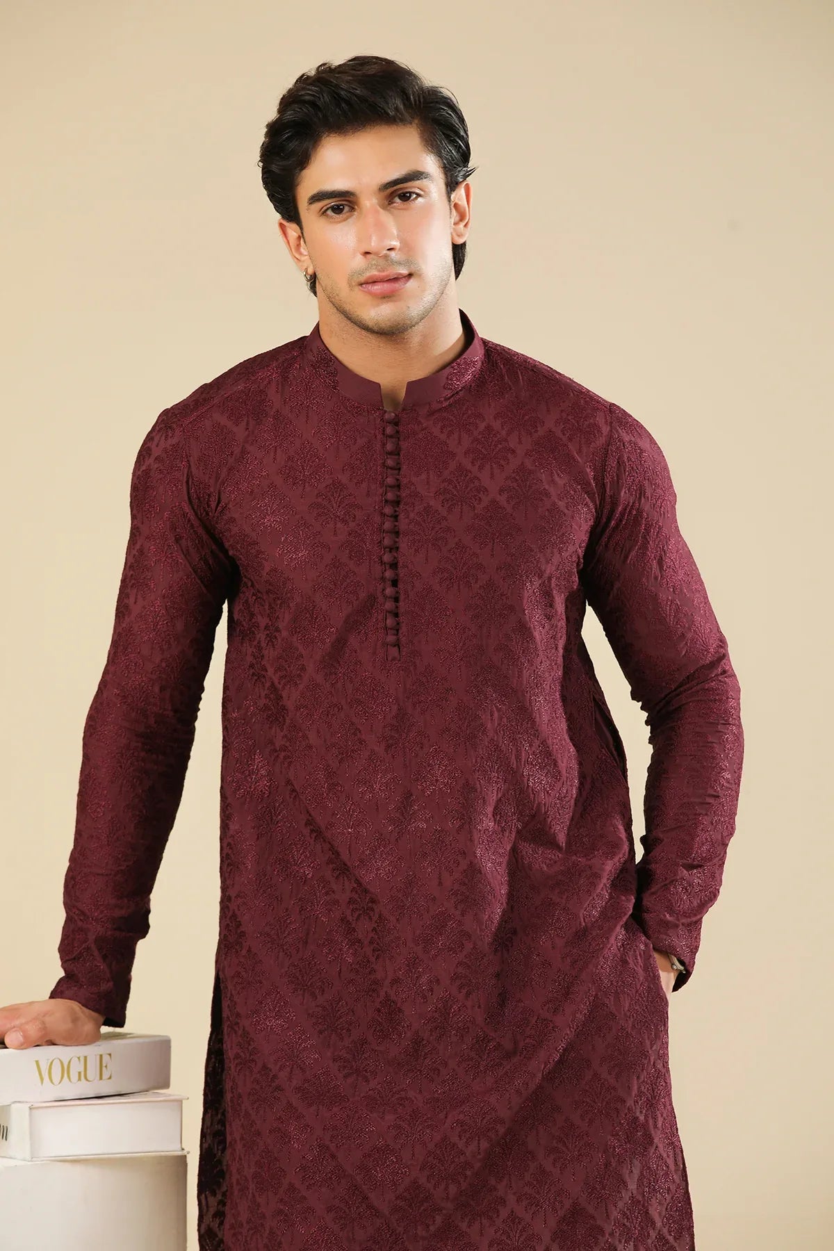 Man wearing a maroon embroidered kurta trouser with a beige background