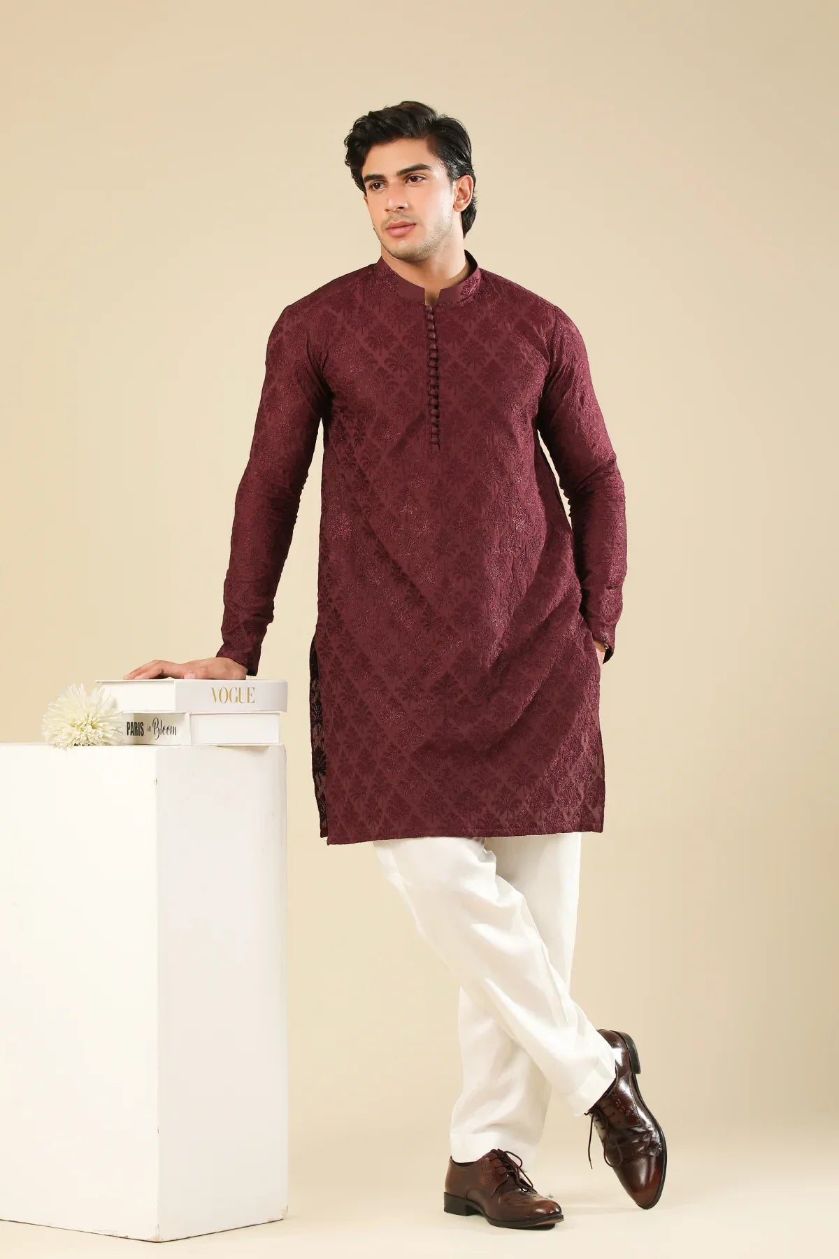 Man wearing a maroon embroidered kurta trouser with a beige background