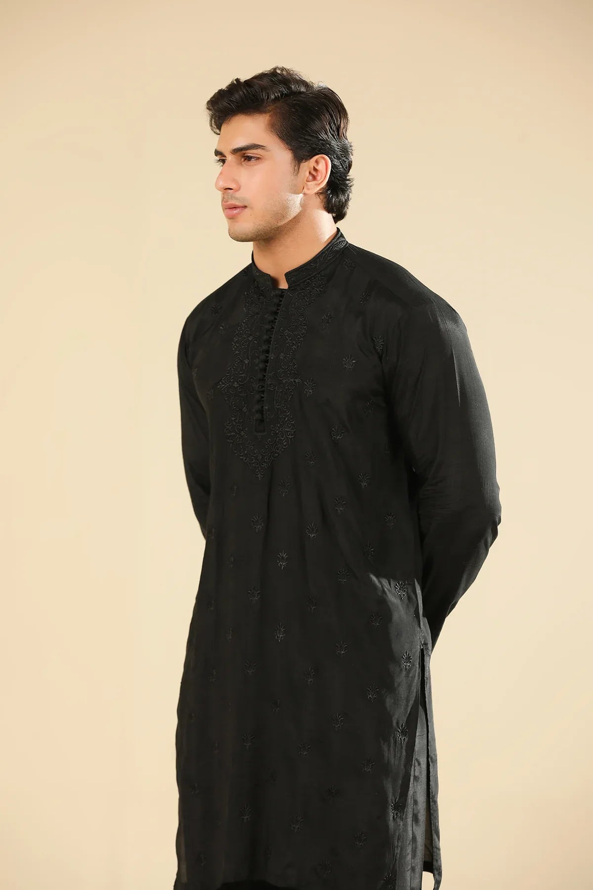Man wearing a black raw silk embroidered kurta trouser against a beige background