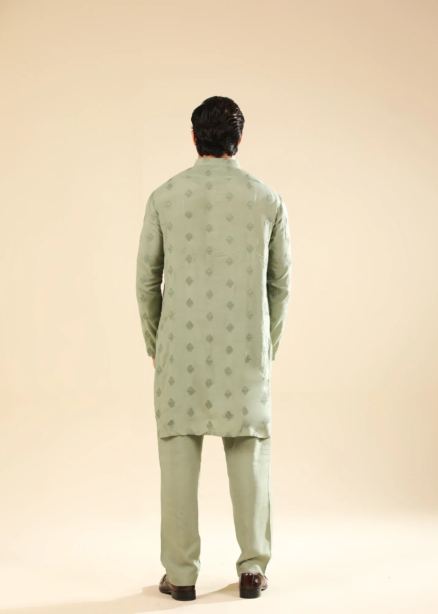 Man wearing a light green raw silk embroidered kurta with a beige backgroung
