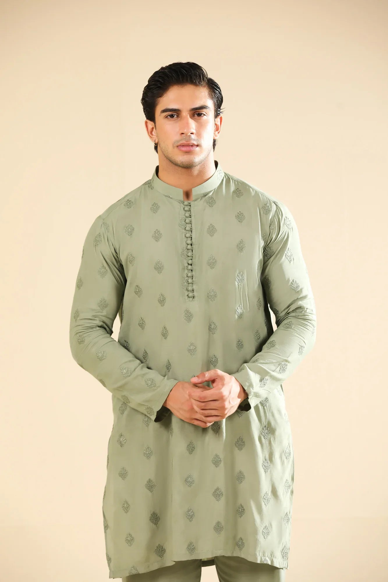 Man wearing a light green raw silk embroidered kurta with a beige backgroung