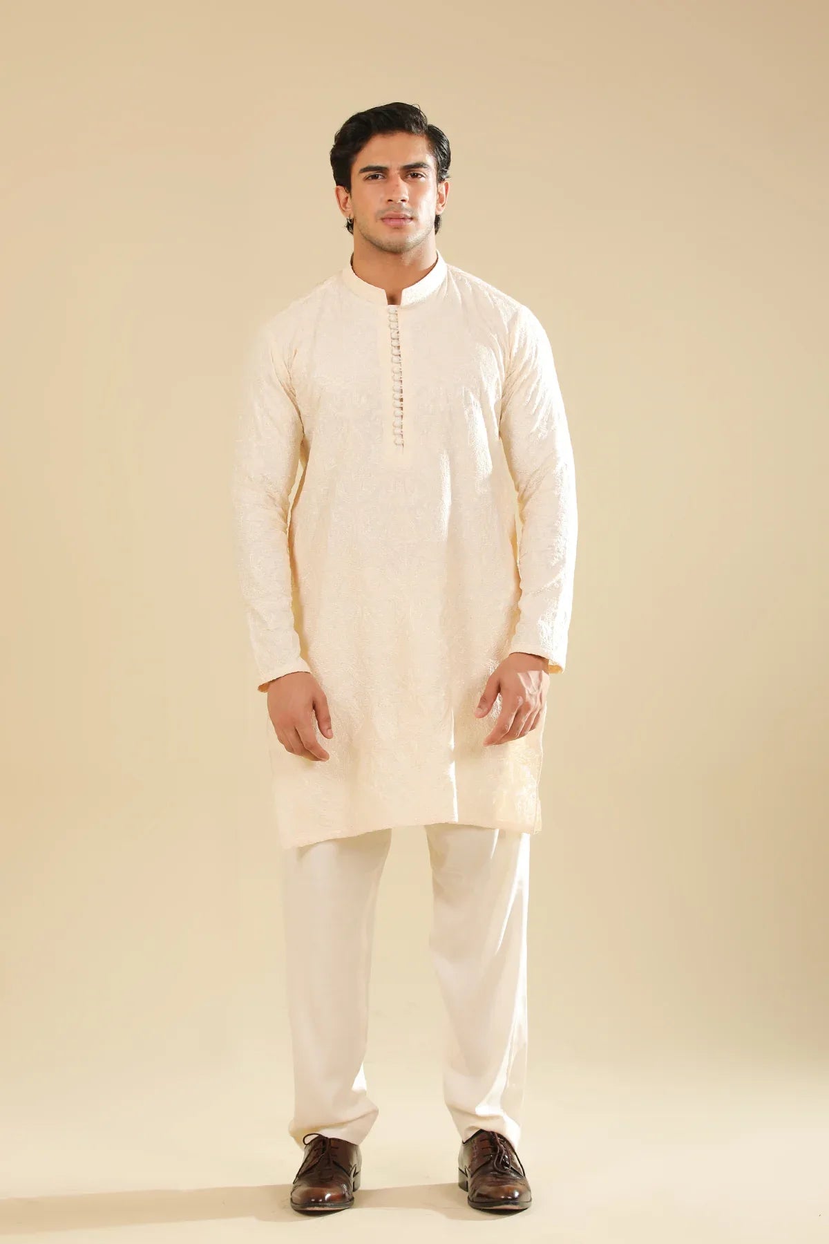 Man wearing a cream raw silk embroidered kurta against a beige background