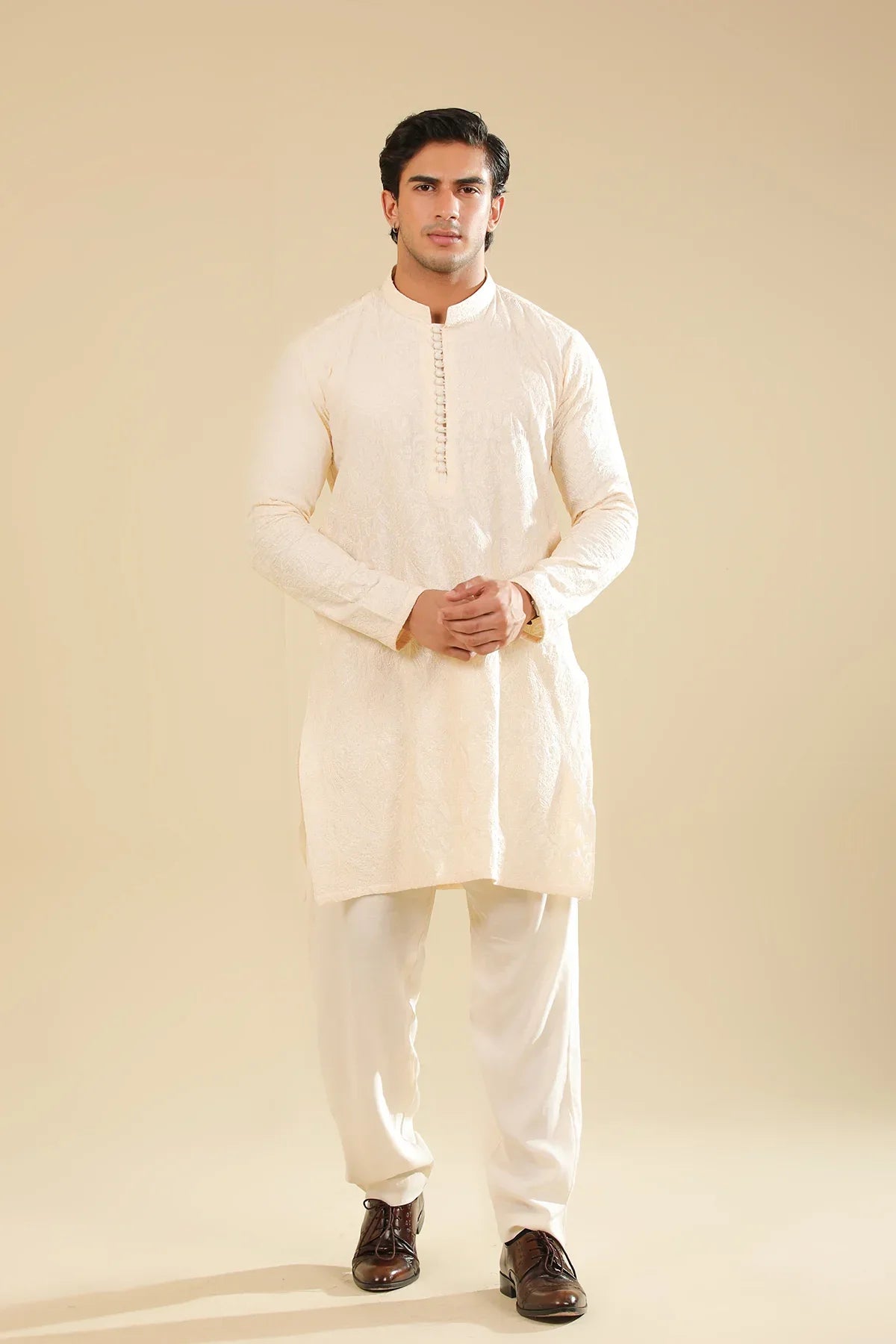 Man wearing a cream raw silk embroidered kurta against a beige background