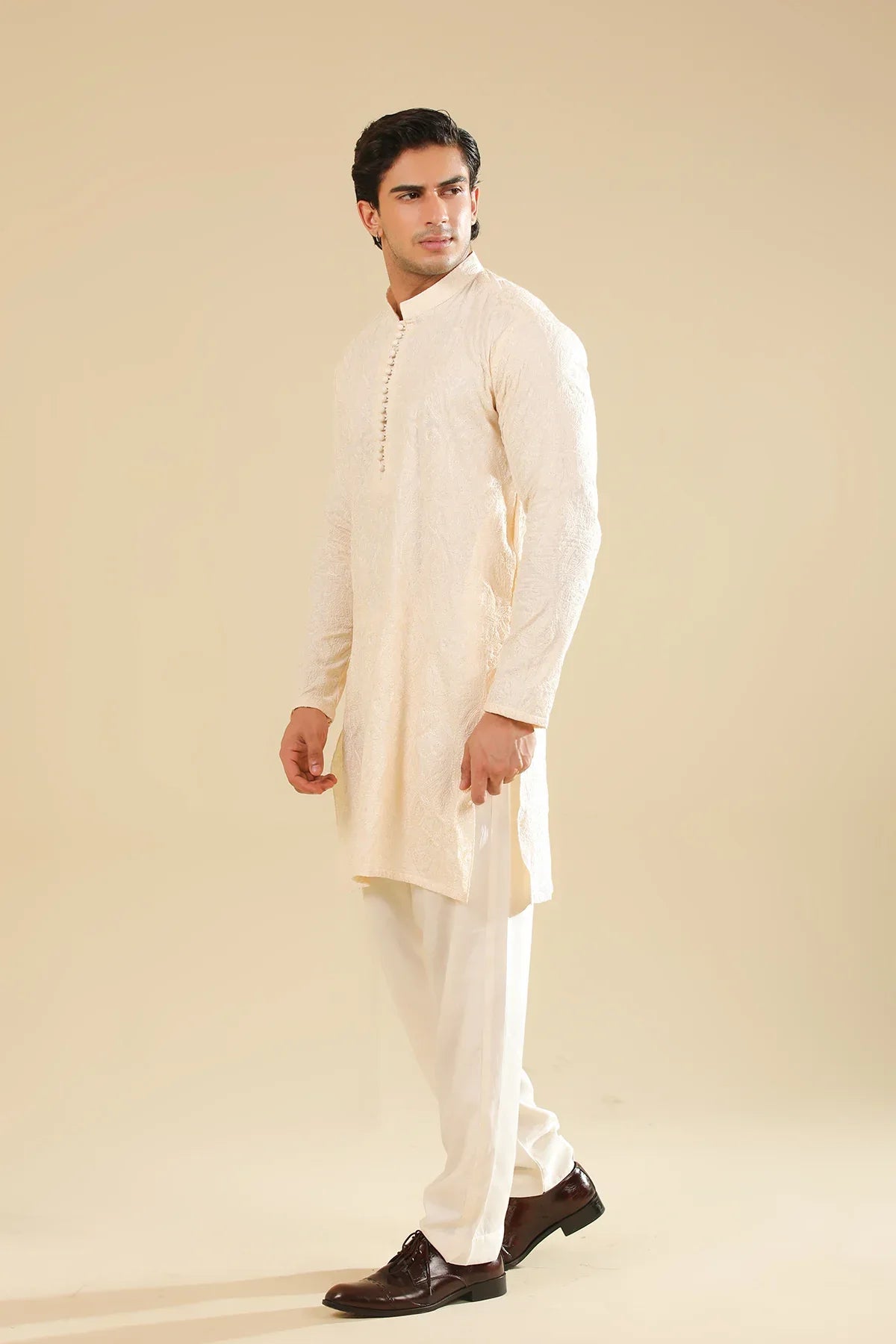 Man wearing a cream raw silk embroidered kurta against a beige background