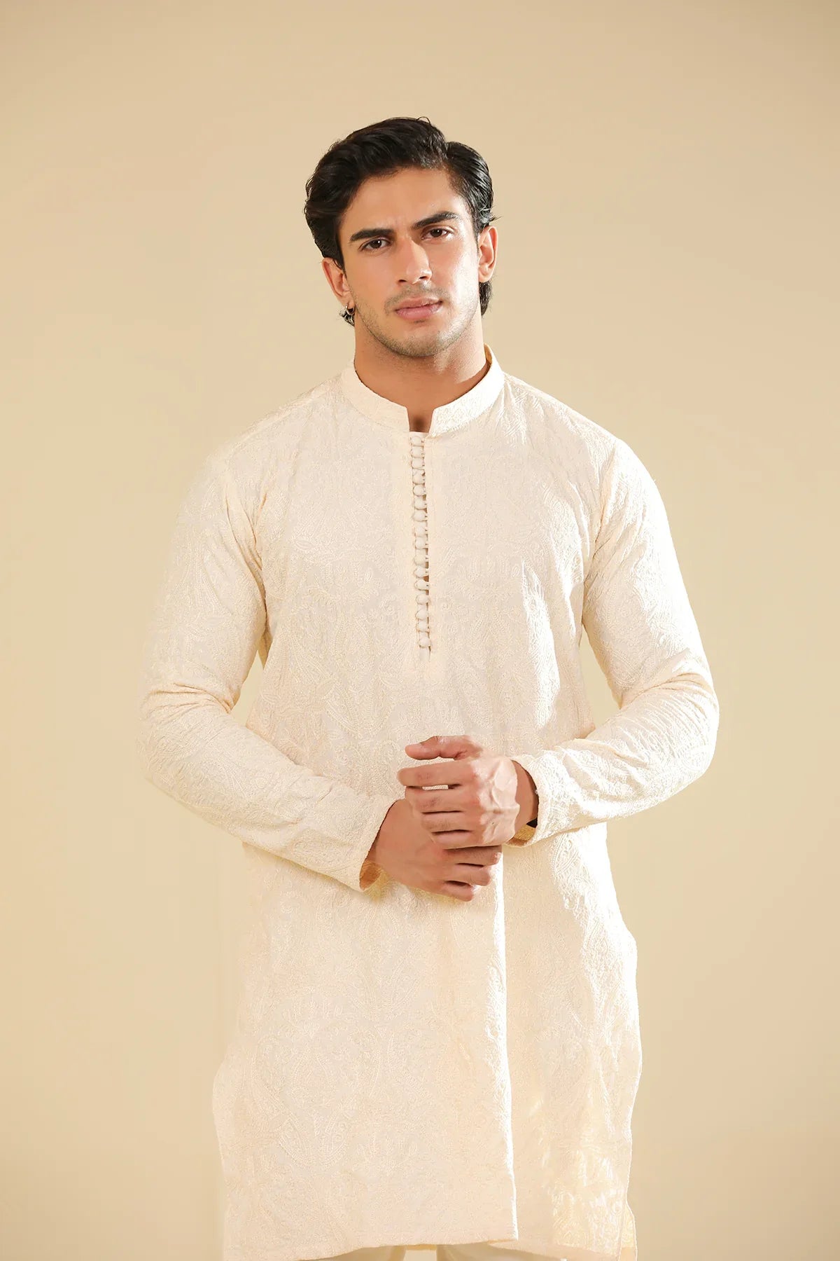 Man wearing a cream raw silk embroidered kurta against a beige background