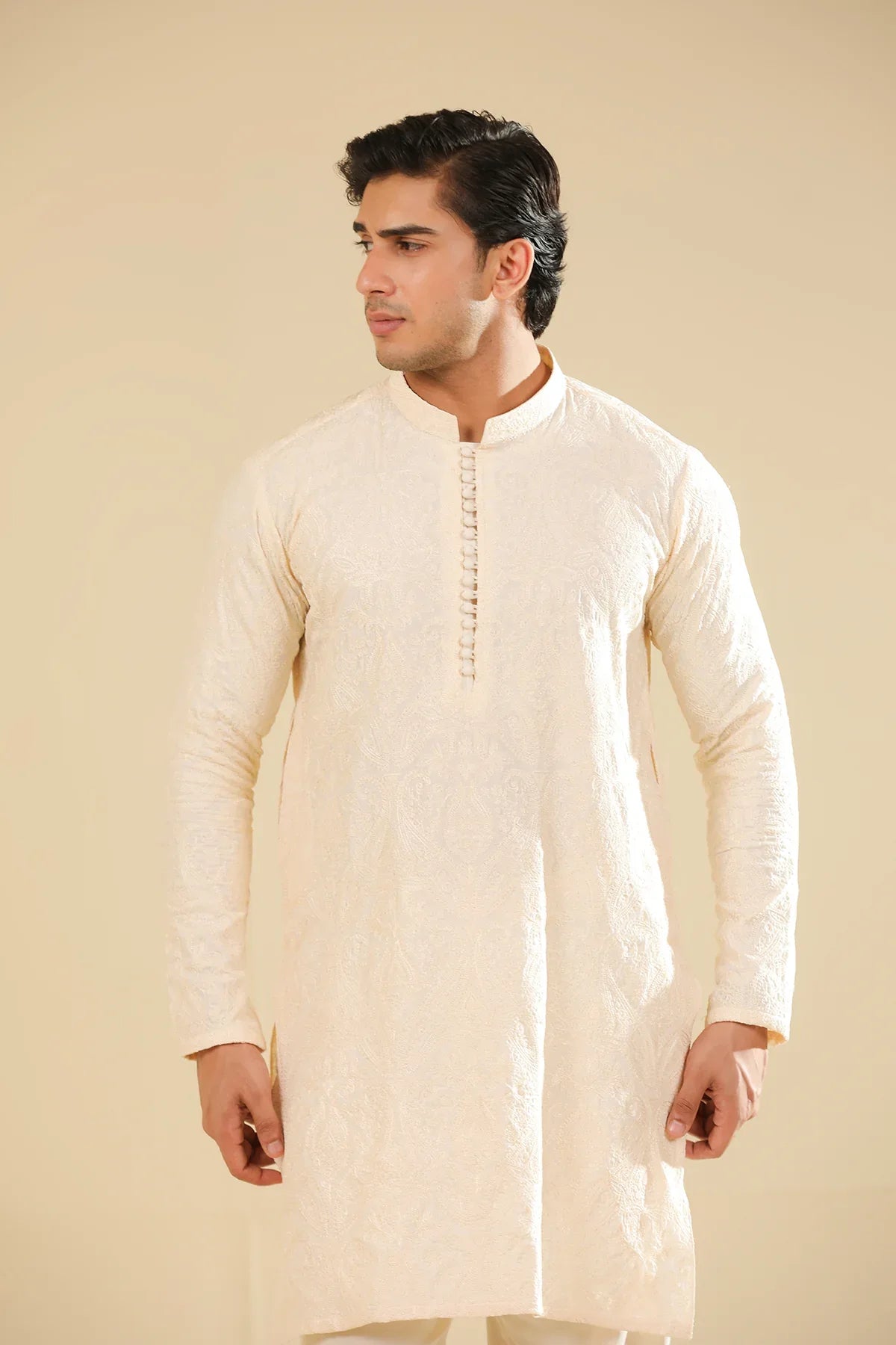 Man wearing a cream raw silk embroidered kurta against a beige background