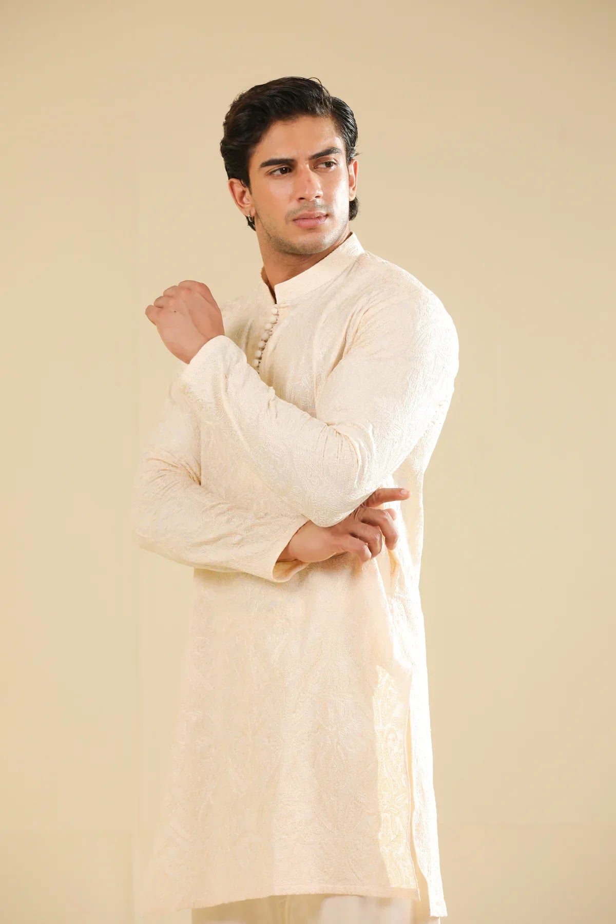 Man wearing a cream raw silk embroidered kurta against a beige background