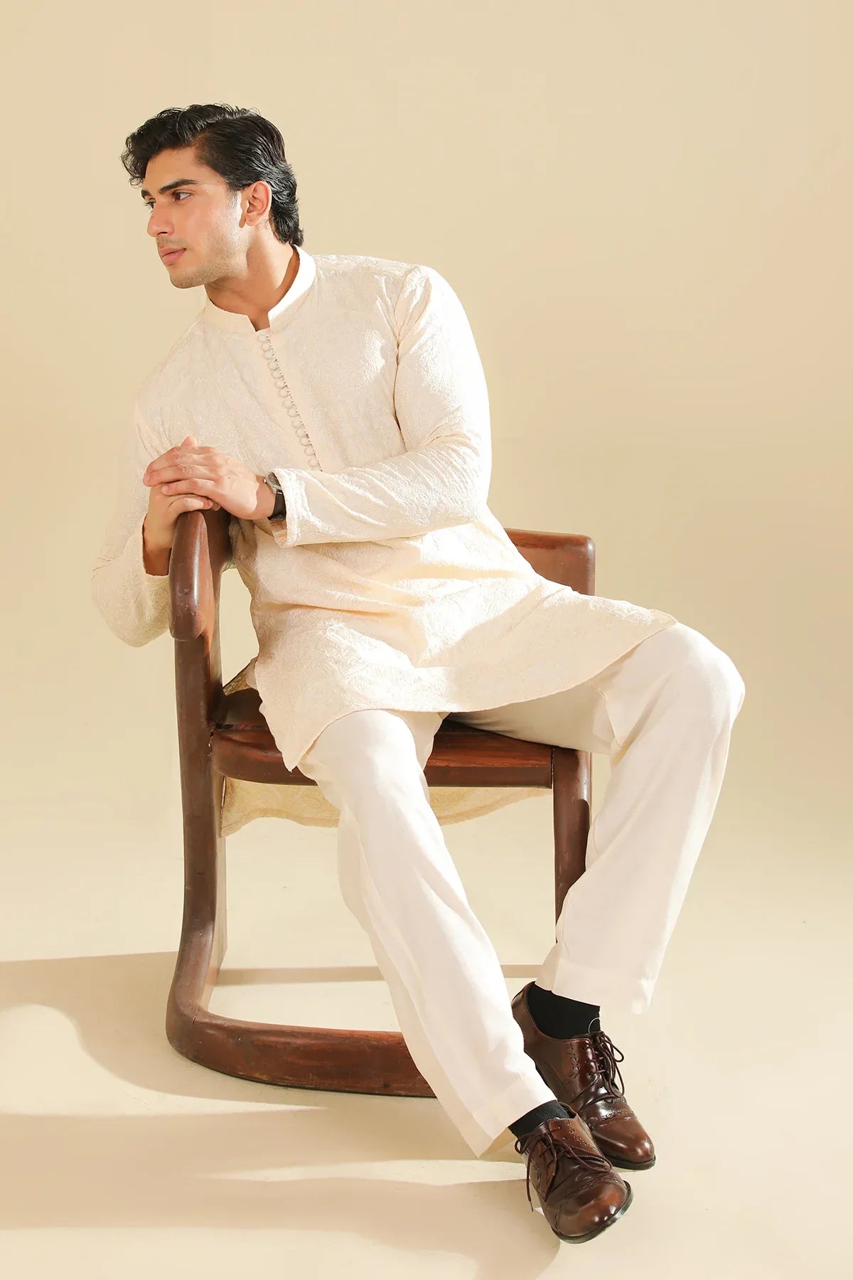 Man wearing a cream raw silk embroidered kurta against a beige background