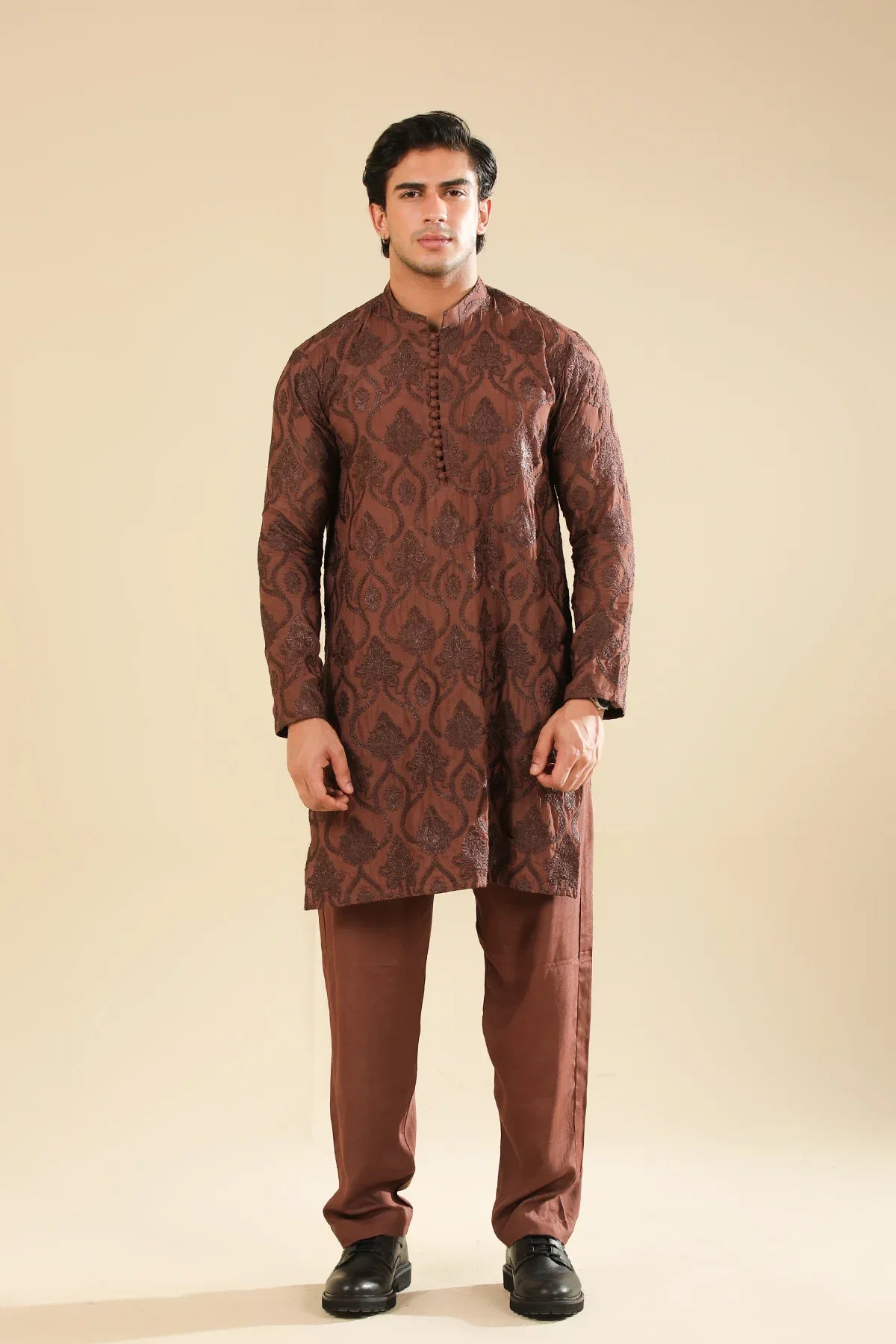 Man wearing a cocoa brown raw silk embroidered kurta trouser against a beige background