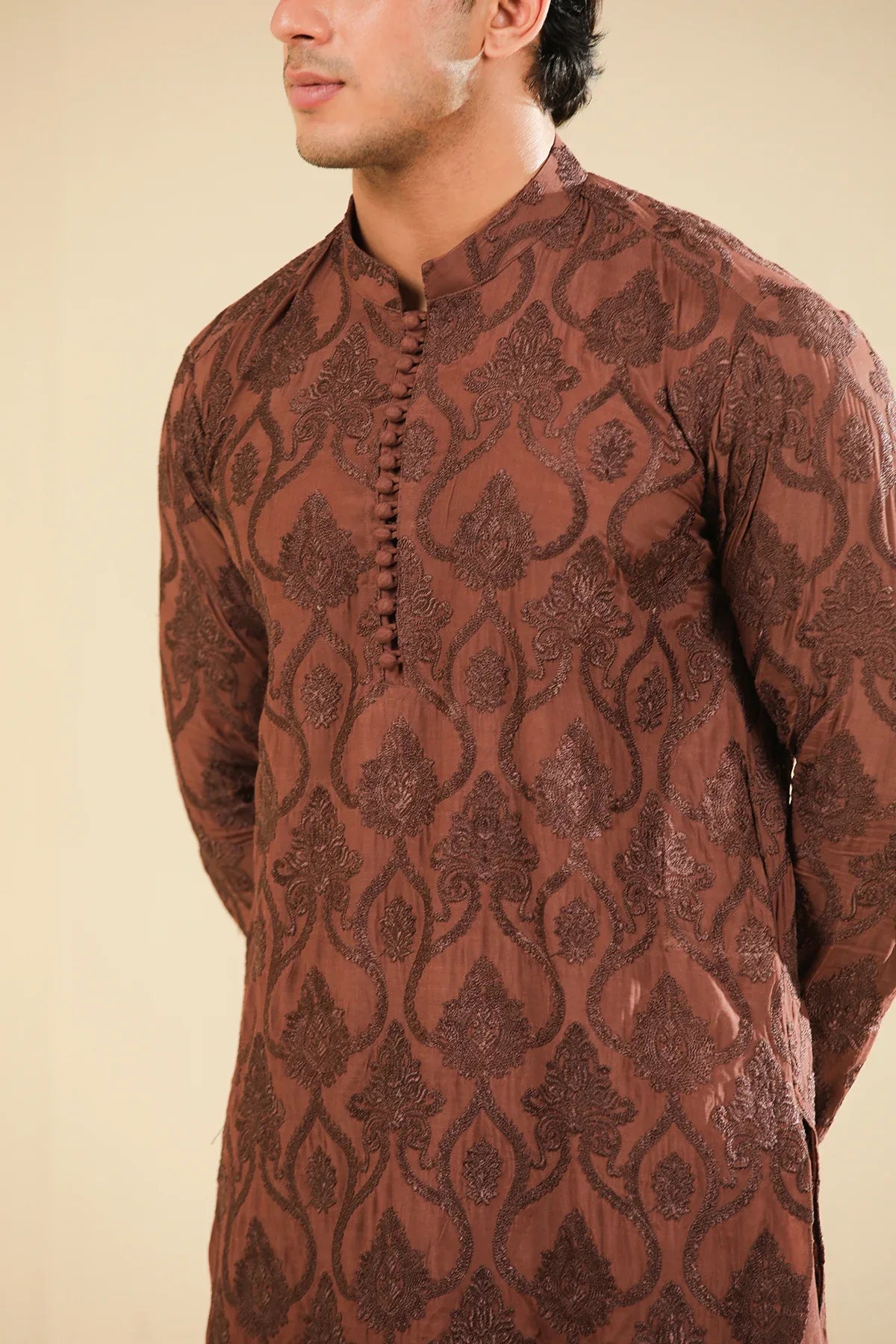 Man wearing a cocoa brown raw silk embroidered kurta trouser against a beige background