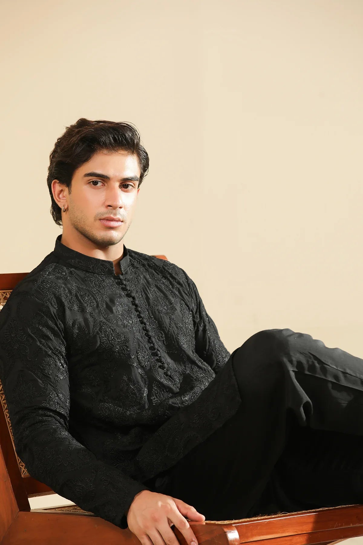 Man wearing a black raw silk embroidered kurta trouser against a beige background