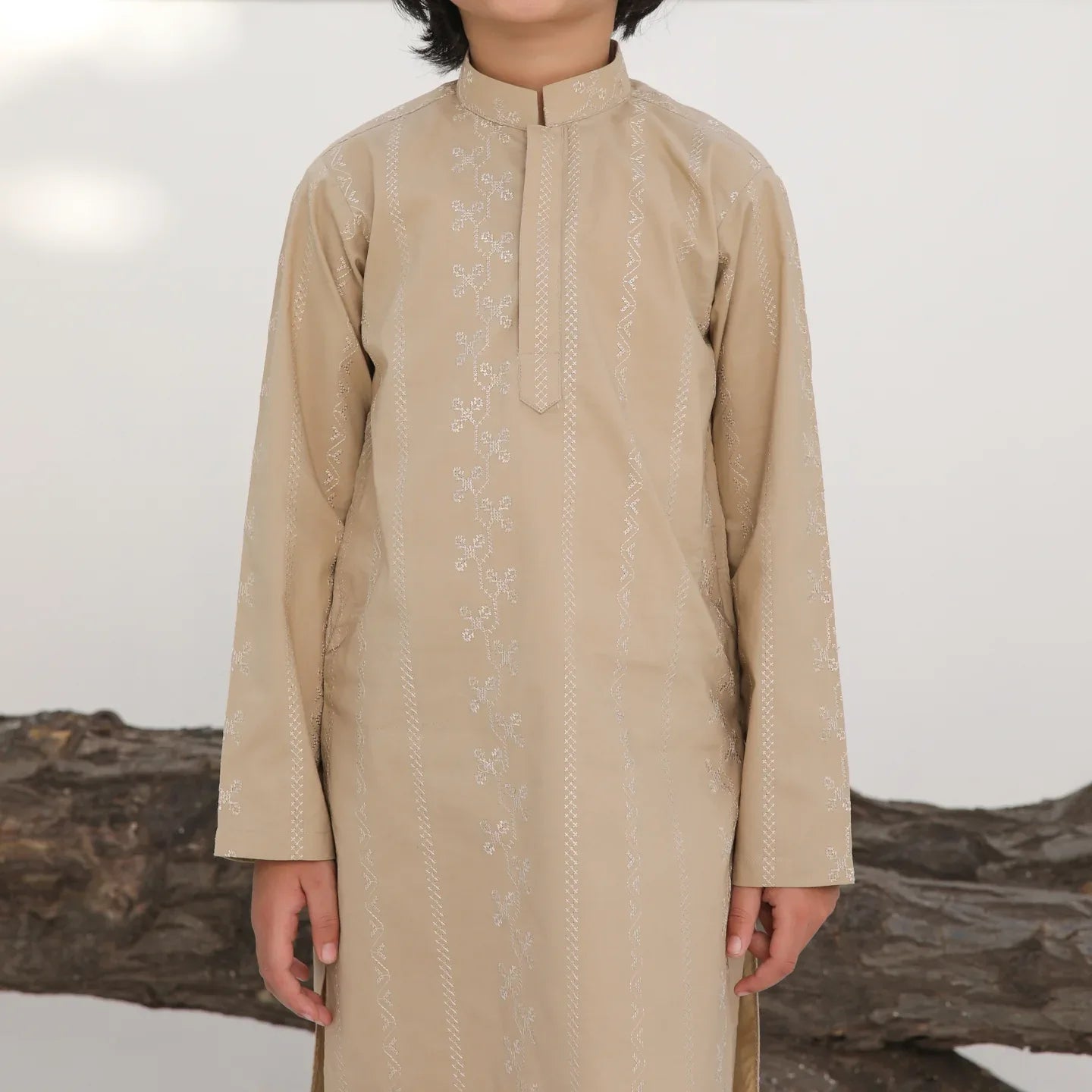 A child wearing a beige embroidered cotton kurta with a mandarin collar and full sleeves, paired with plain beige cotton trousers.