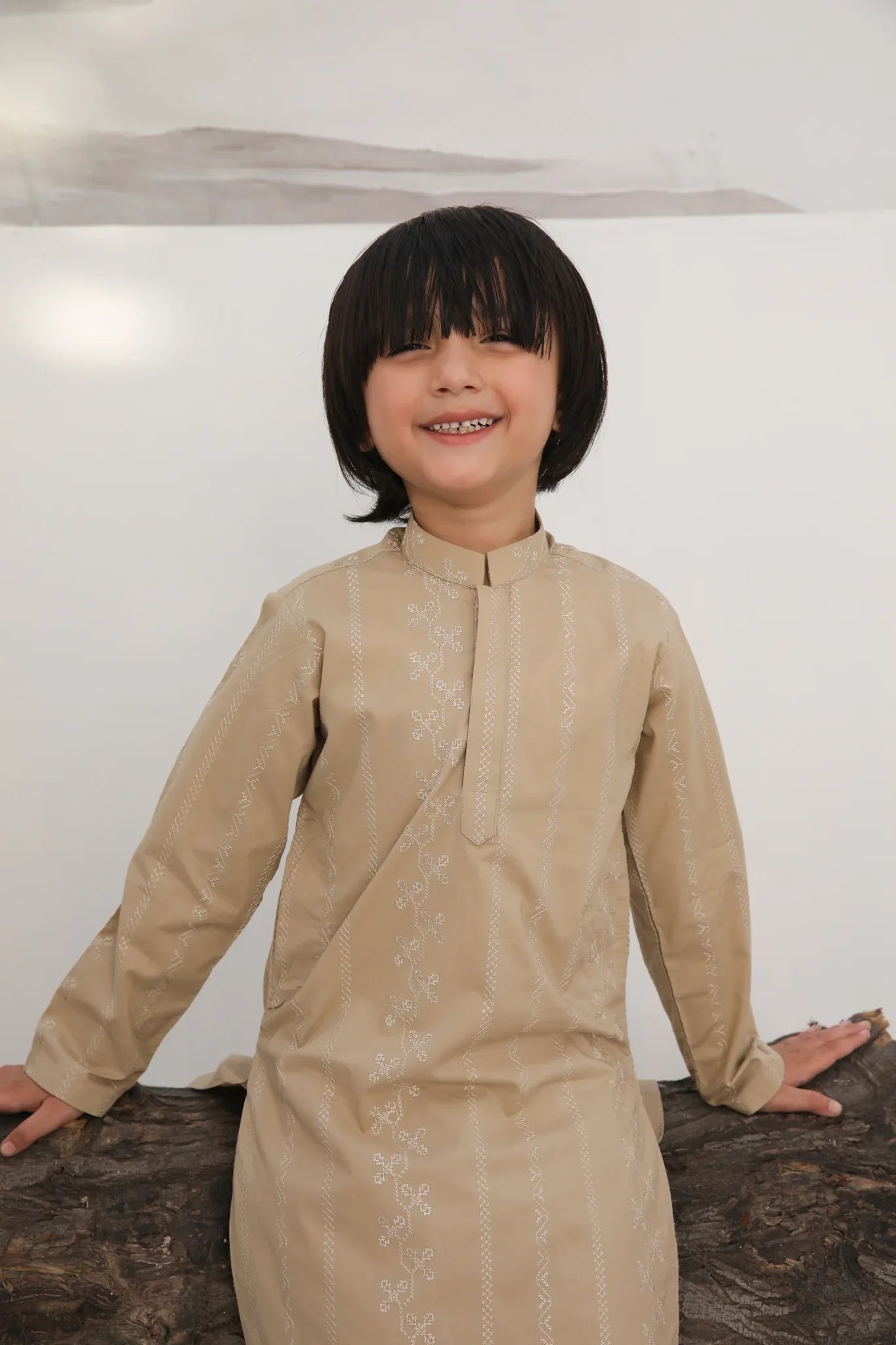 A child wearing a beige embroidered cotton kurta with a mandarin collar and full sleeves, paired with plain beige cotton trousers.