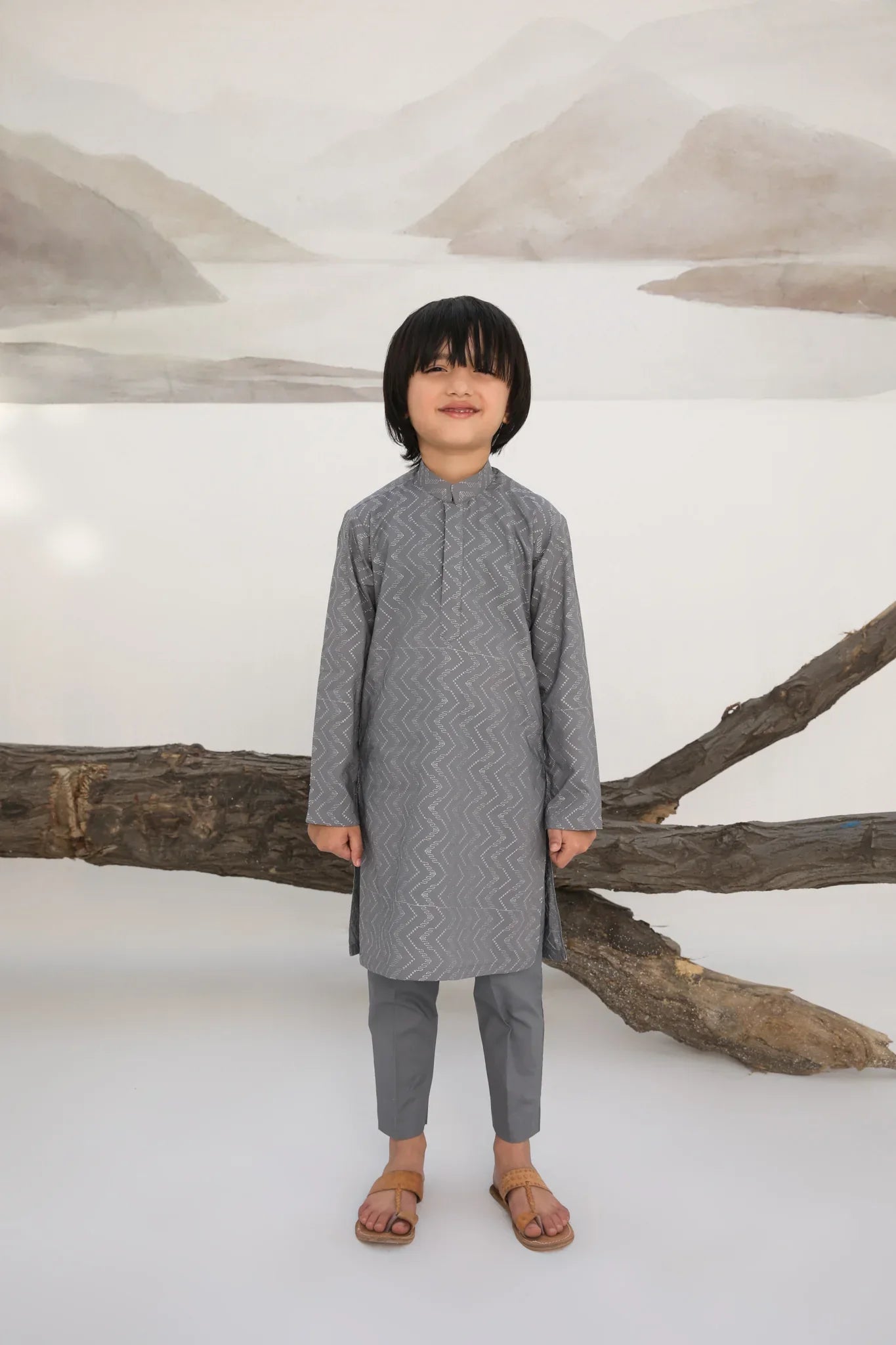 A child wearing a light grey embroidered kurta with a mandarin collar and full sleeves, paired with plain cotton trousers.