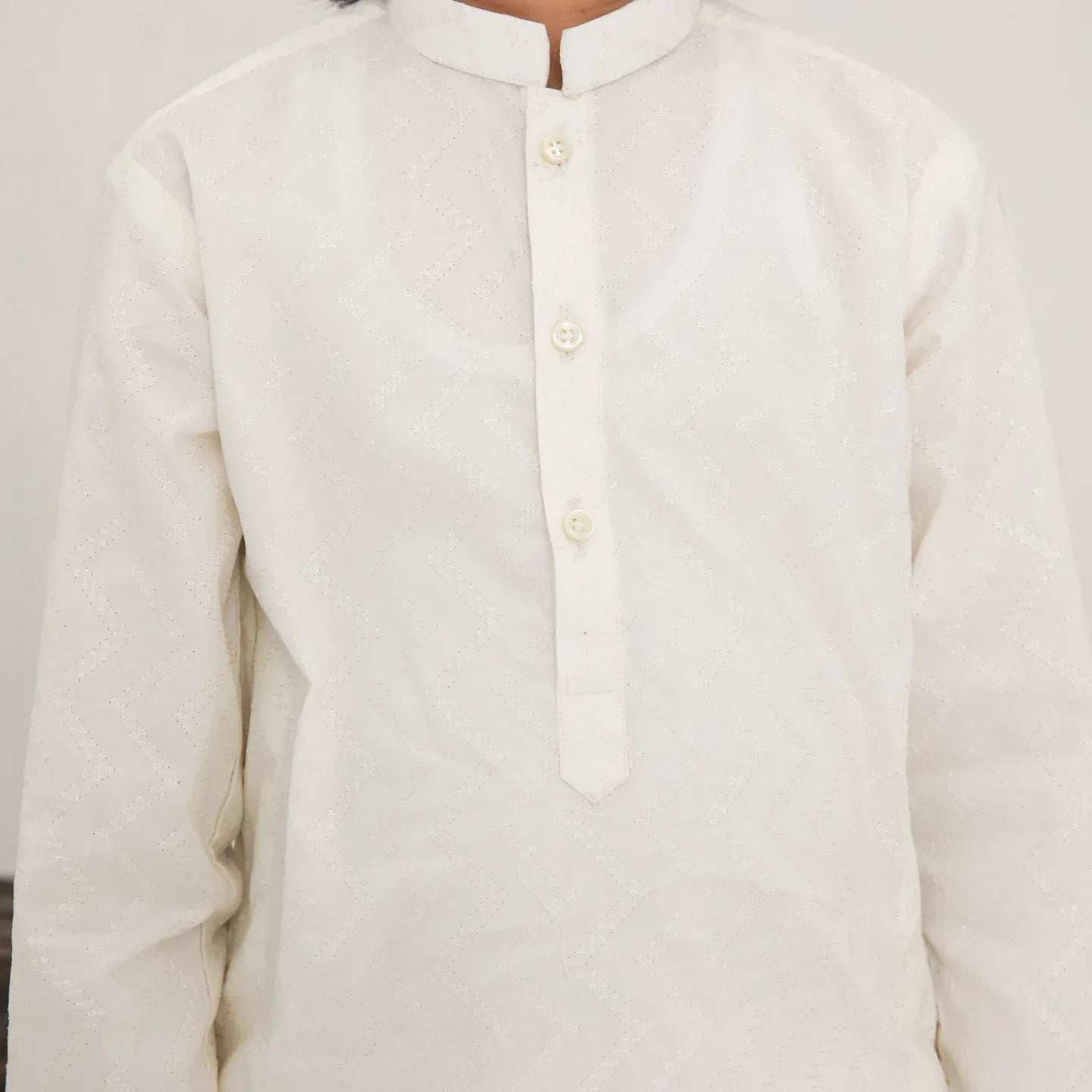 A child wearing a white cotton embroidered kurta trouser
