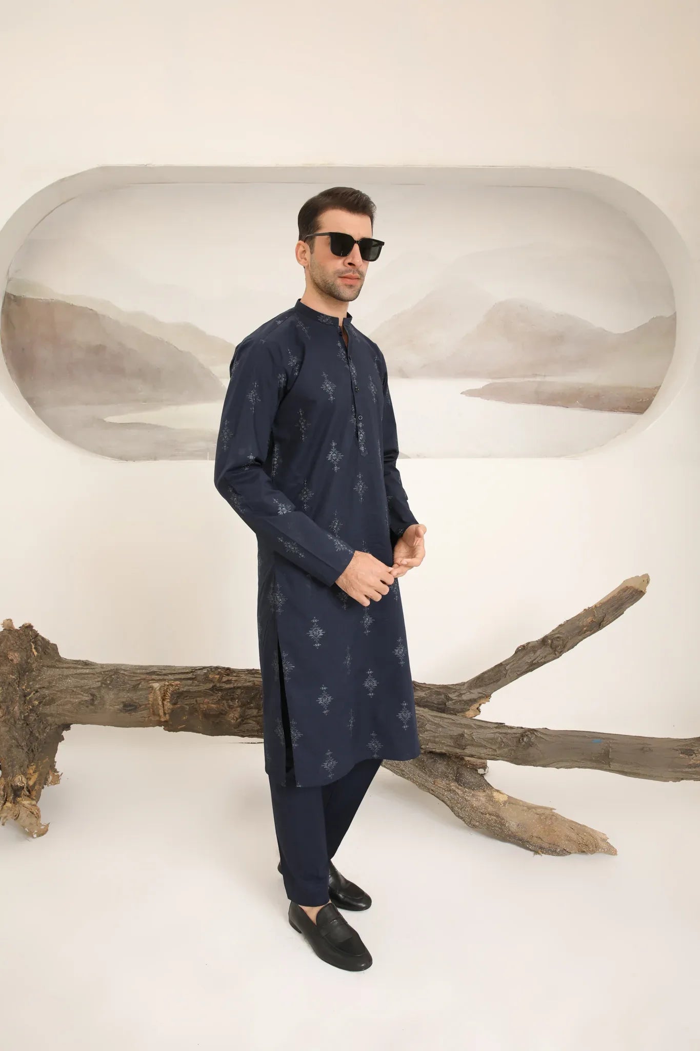 A man wearing a navy blue cotton embroidered kurta and trouser with a mandarin collar and full sleeves.