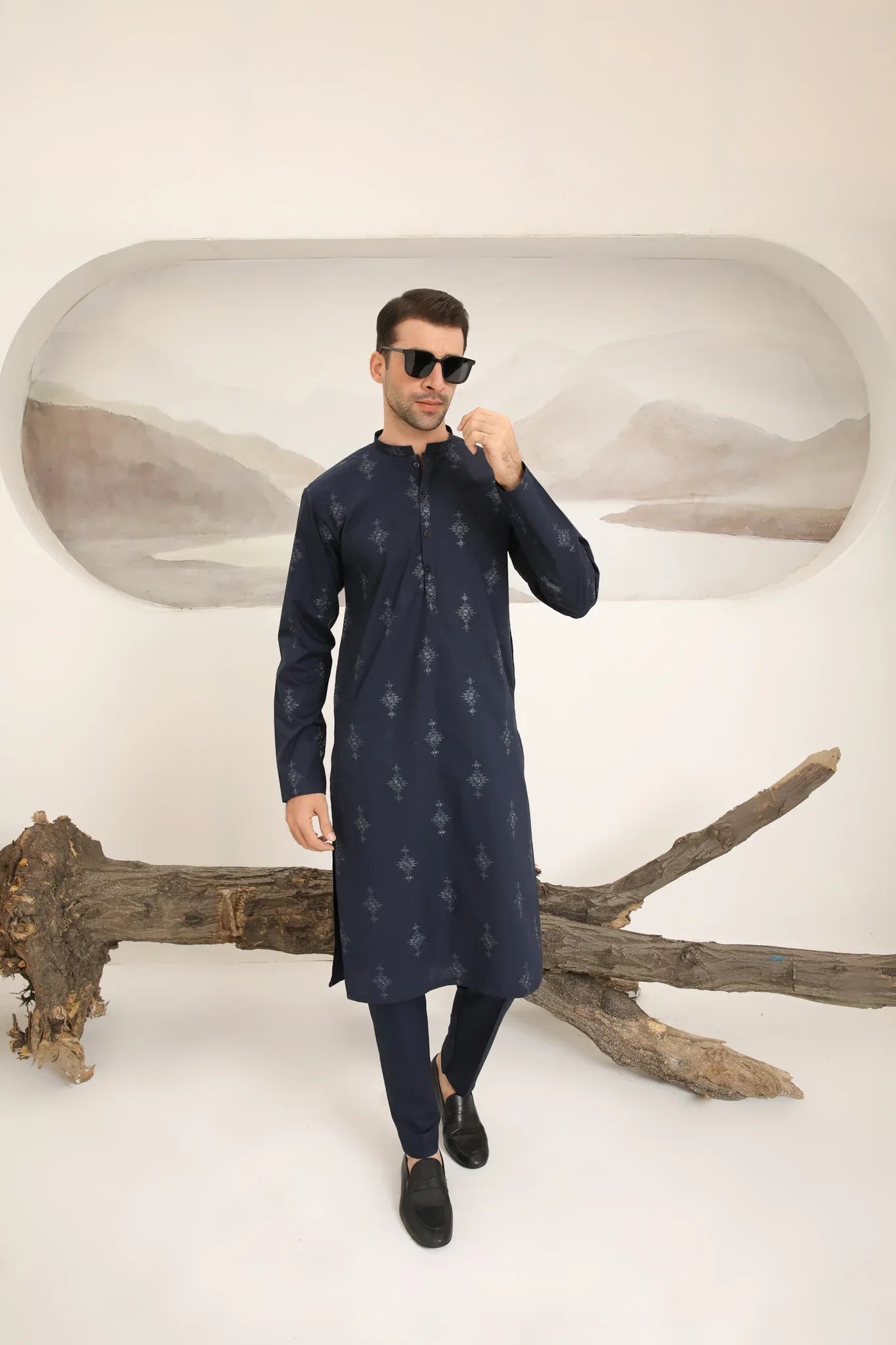 A man wearing a navy blue cotton embroidered kurta and trouser with a mandarin collar and full sleeves.