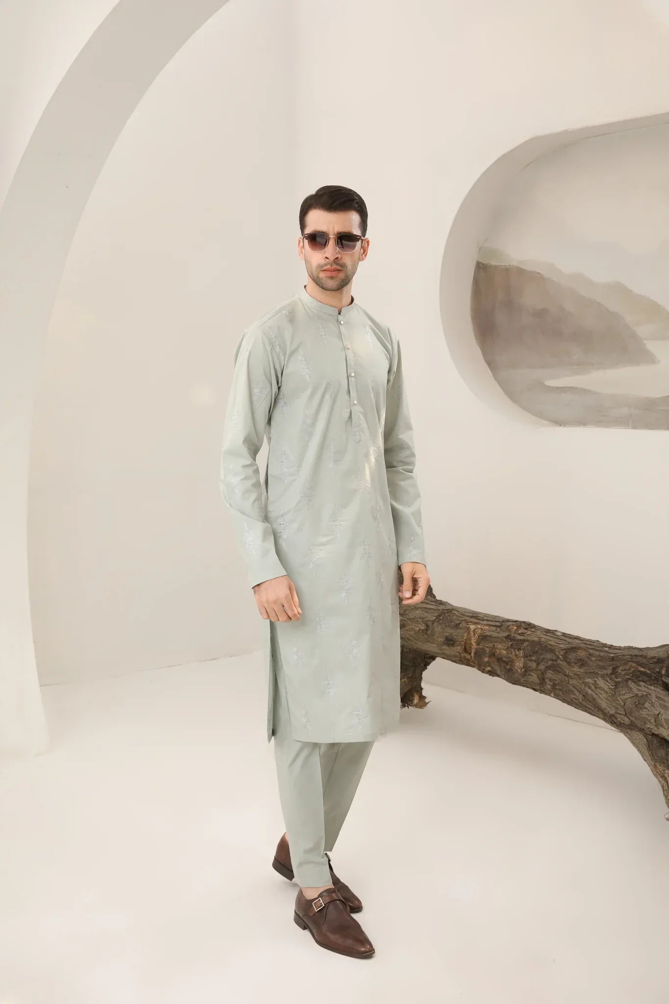 A man wearing a mint green embroidered kurta with full sleeves and a mandarin collar, paired with plain trousers.