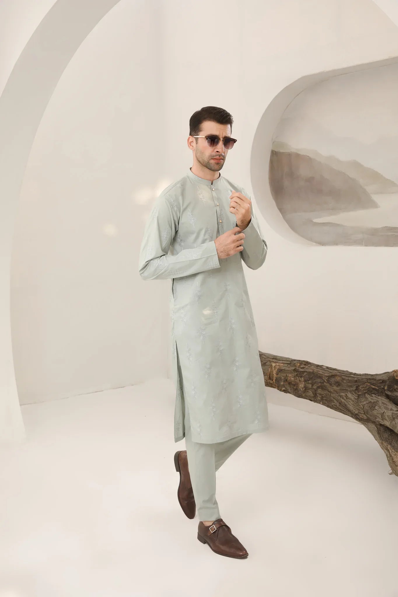 A man wearing a mint green embroidered kurta with full sleeves and a mandarin collar, paired with plain trousers.