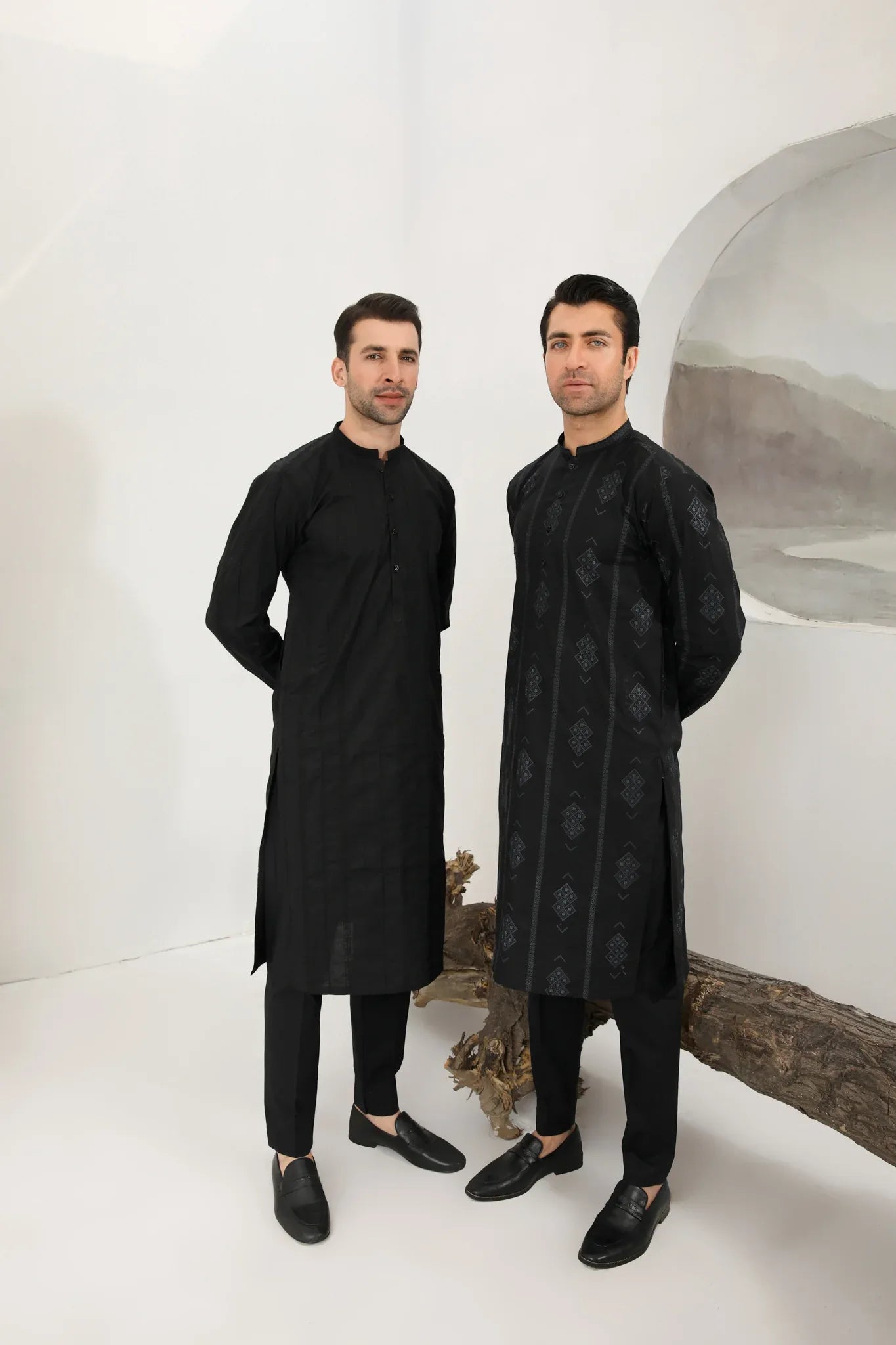 A man wearing a black embroidered kurta with full sleeves and a mandarin collar, paired with plain trousers.