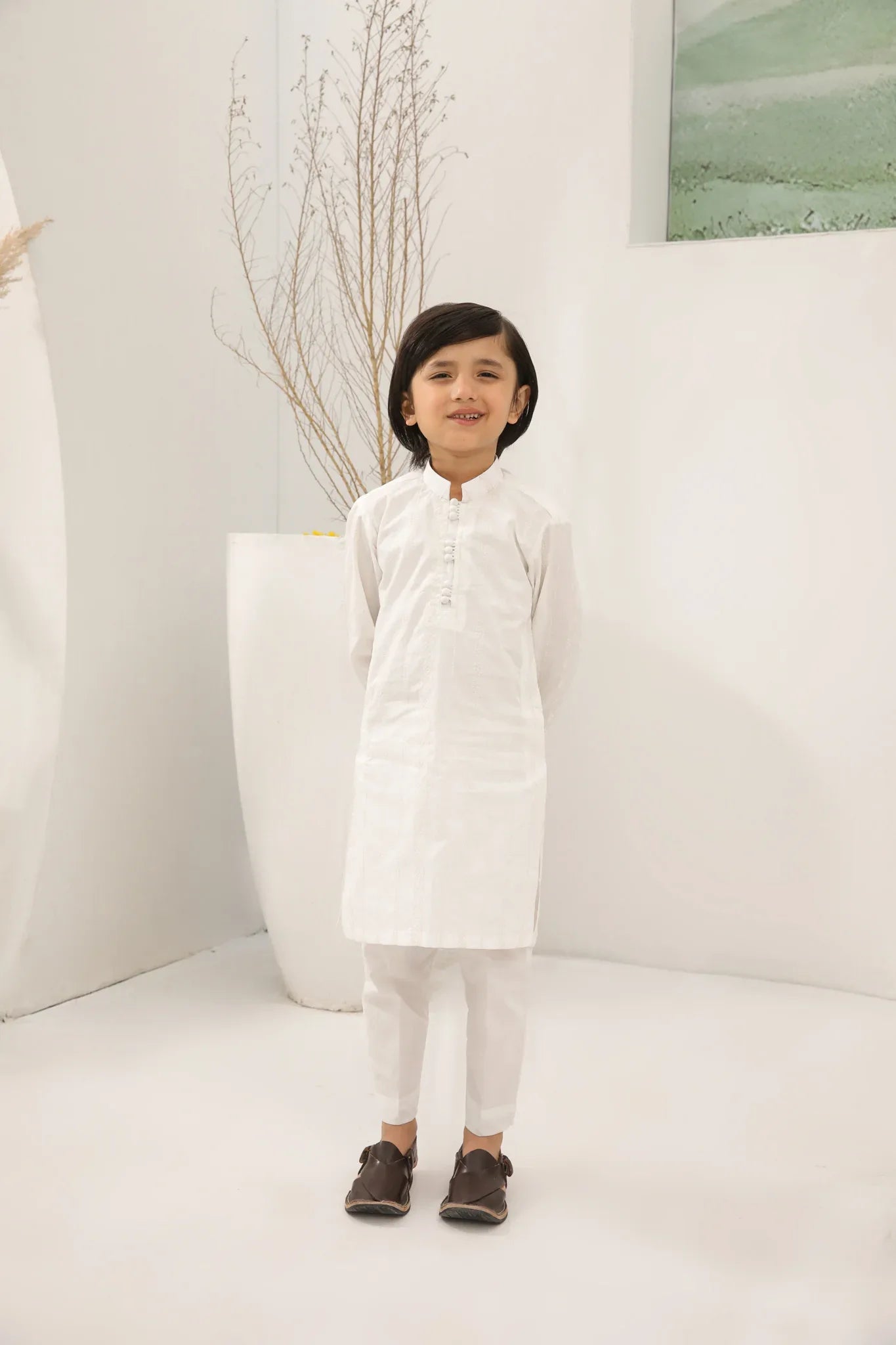 A child wearing an off white cotton embroidered kurta trouser