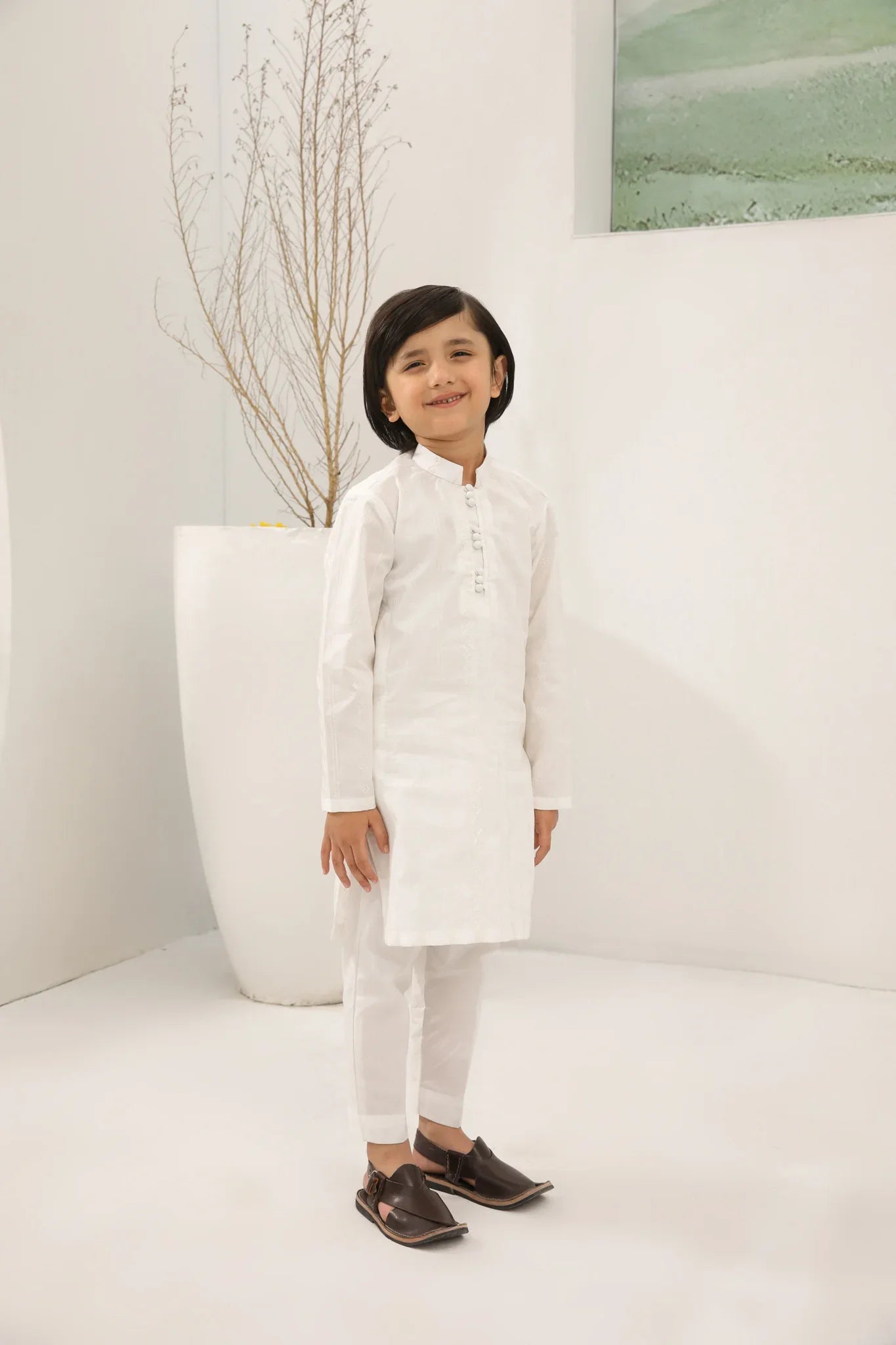 A child wearing an off white cotton embroidered kurta trouser
