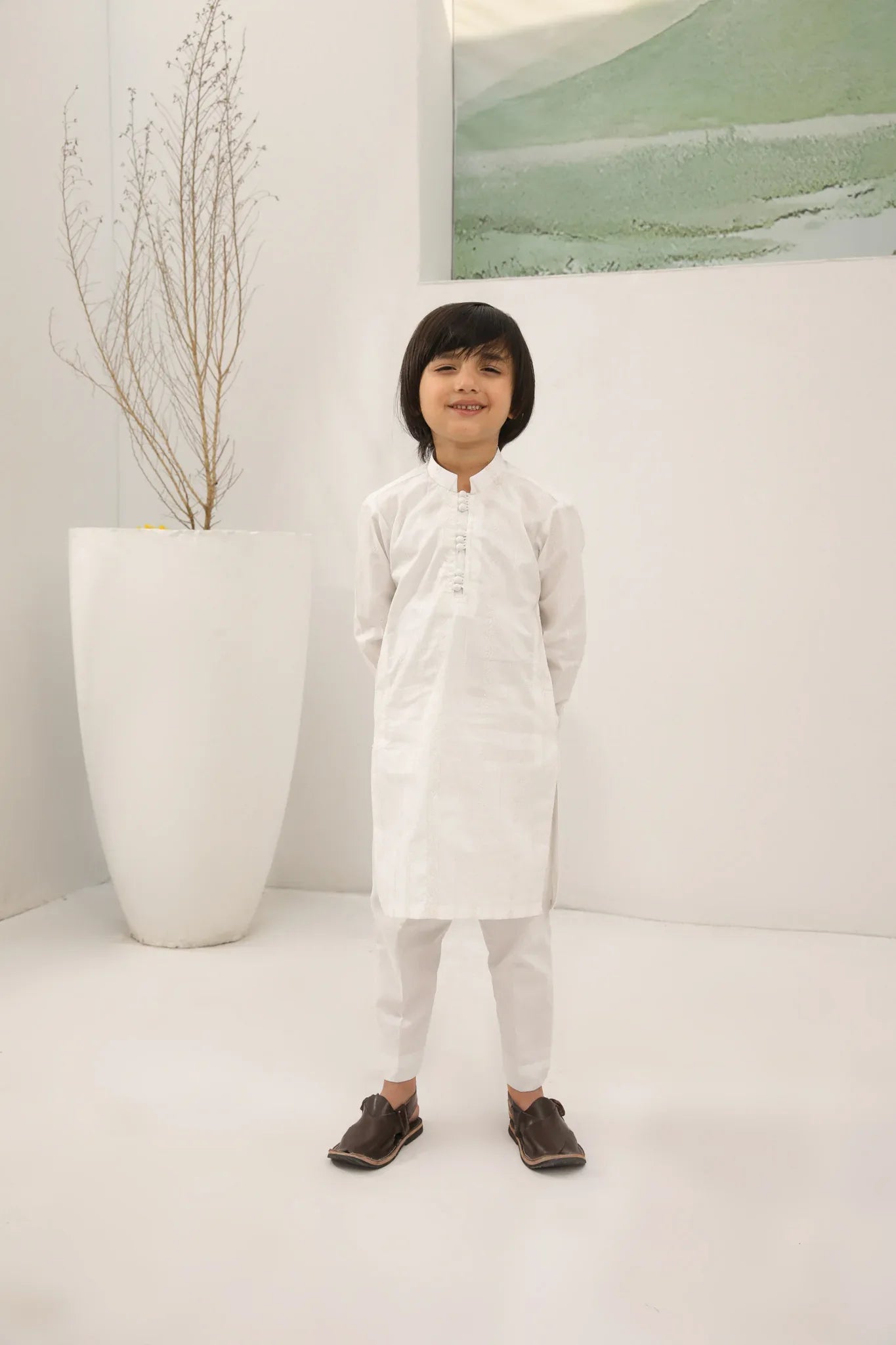 A child wearing an off white cotton embroidered kurta trouser