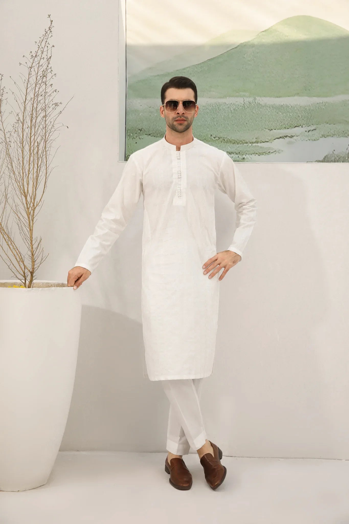 A man wearing a white embroidered kurta trouser with full sleeves in soft cotton fabric.