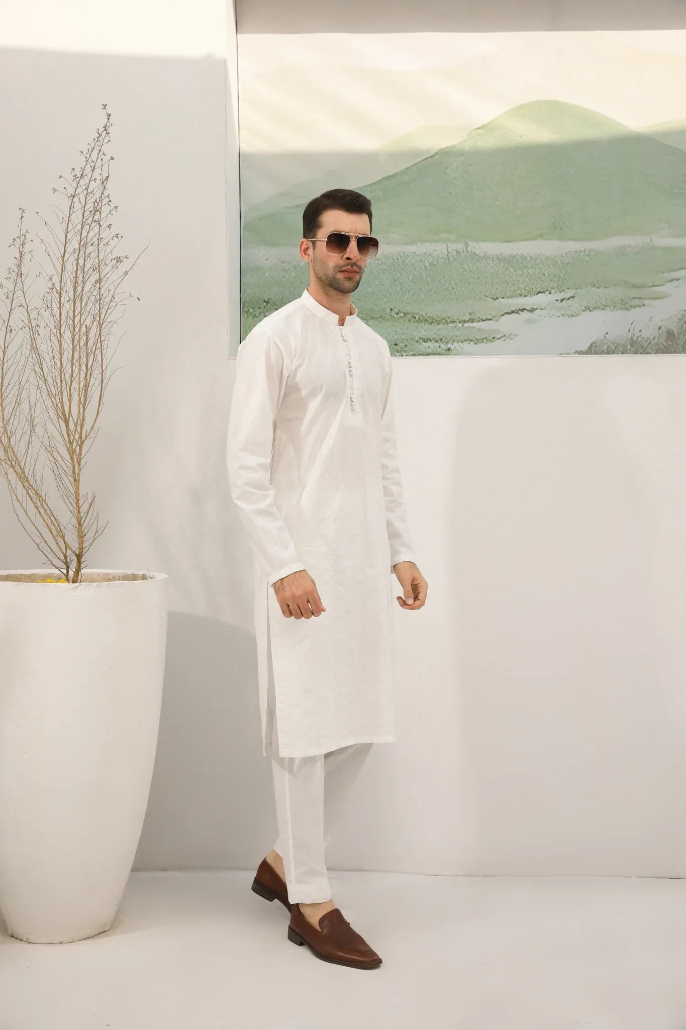 A man wearing a white embroidered kurta trouser with full sleeves in soft cotton fabric.