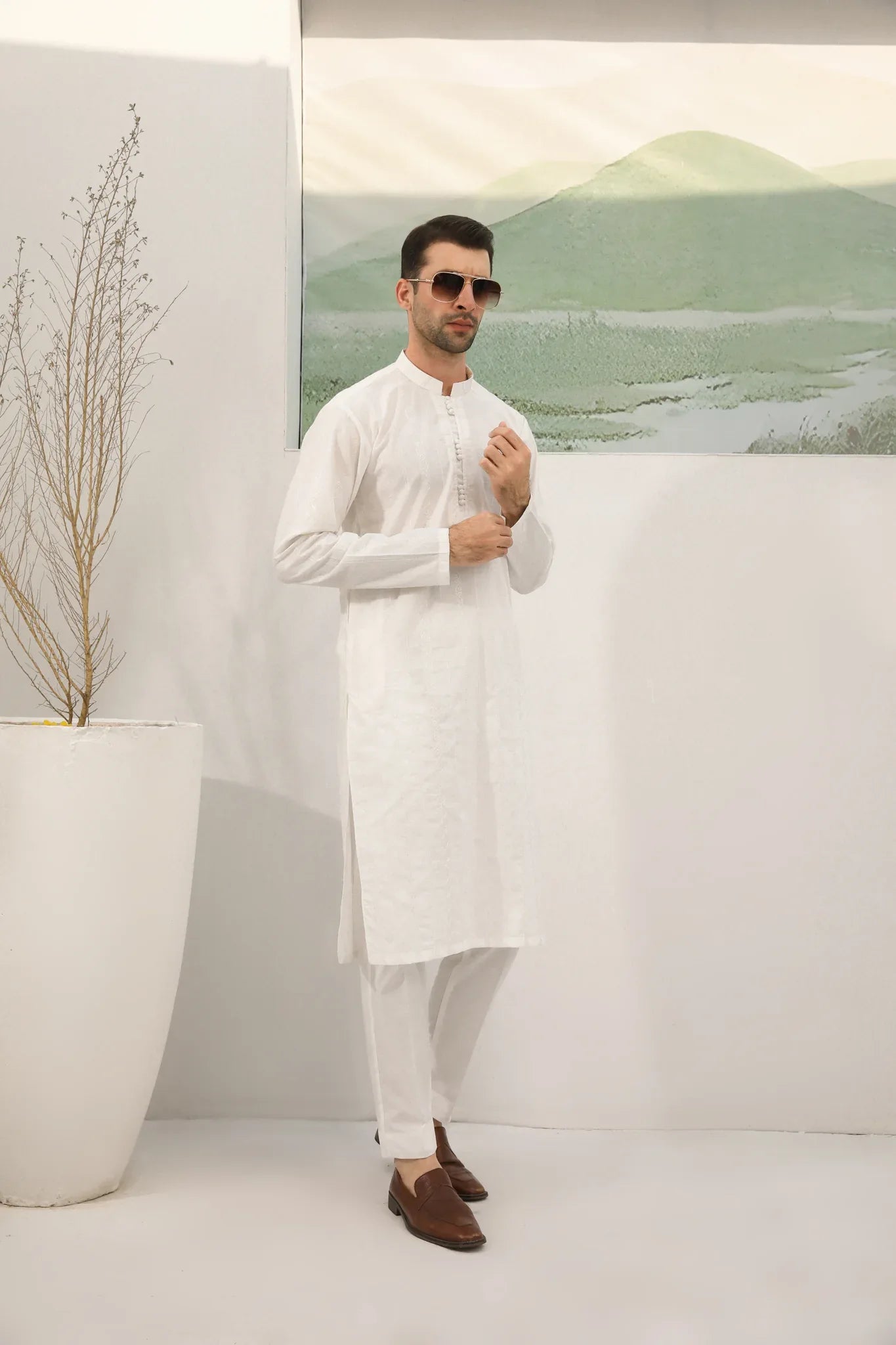 A man wearing a white embroidered kurta trouser with full sleeves in soft cotton fabric.
