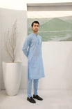 A man standing in a room wearing sky blue embroidered kurta and plain trouser in soft cotton fabric .