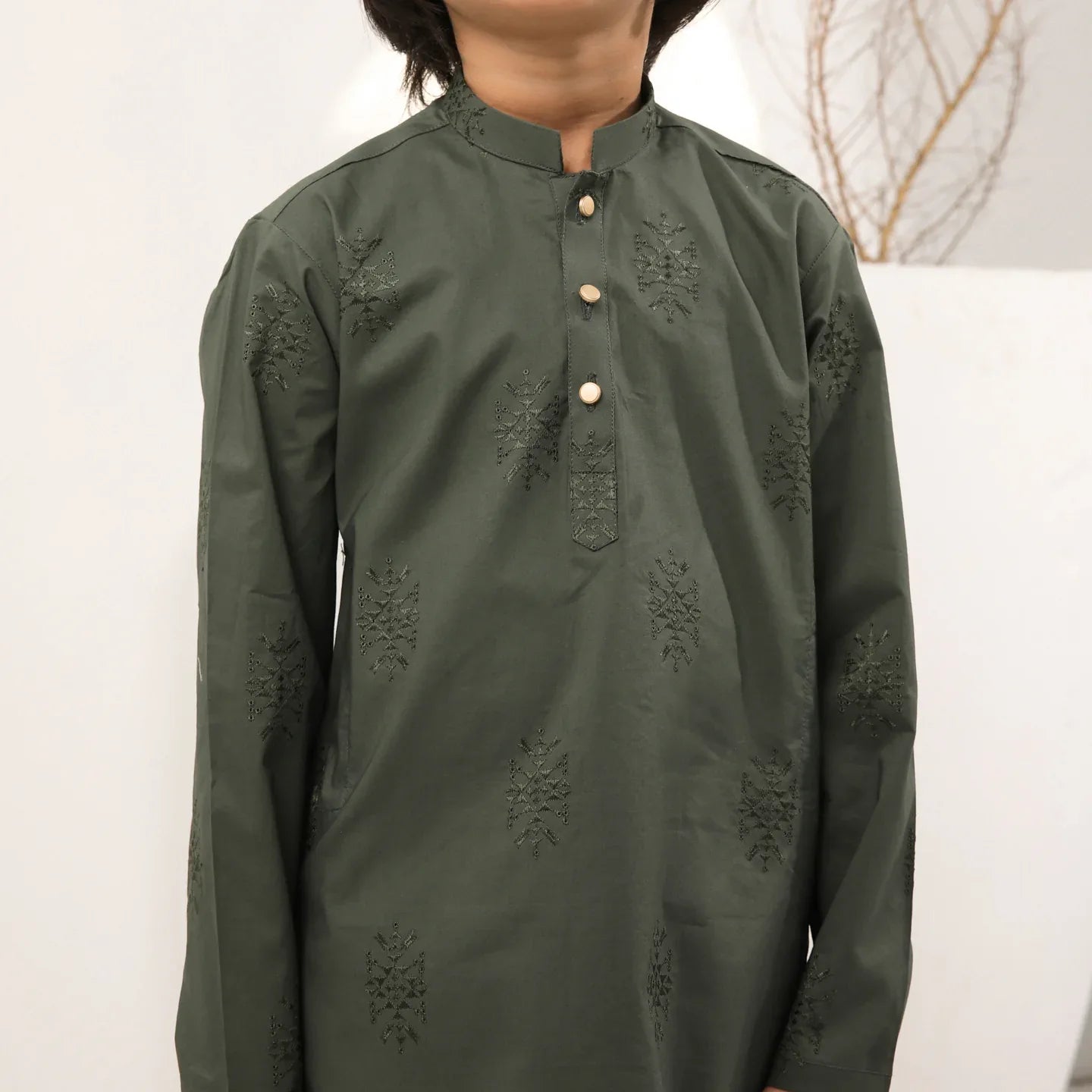 A child standing wearing an army green cotton embroidered kurta with full sleeves and a mandarin collar, paired with plain cotton trousers.