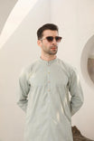A man wearing a mint green embroidered kurta with full sleeves and a mandarin collar, paired with plain trousers. 